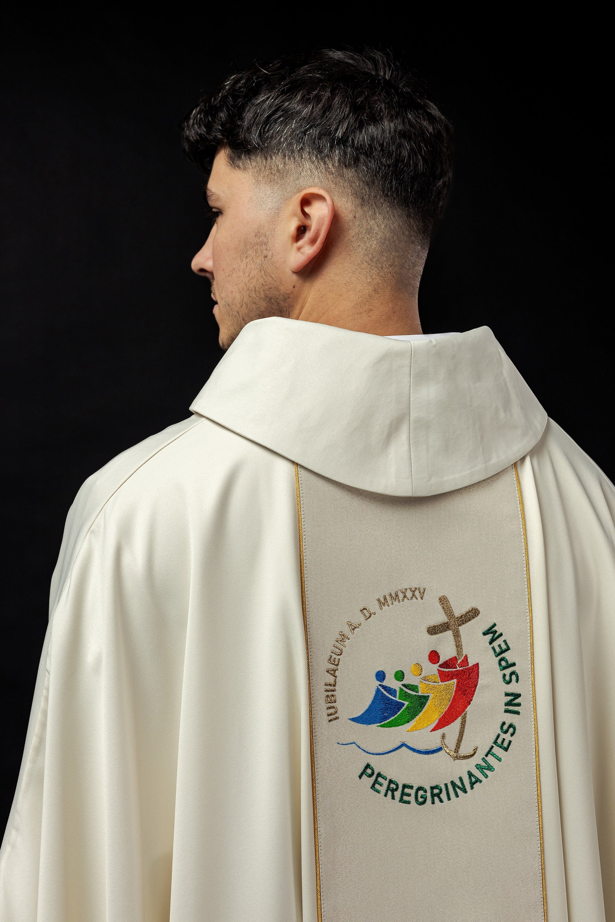 Casula creme com faixa bordada e logo do Jubileu Roma 2025