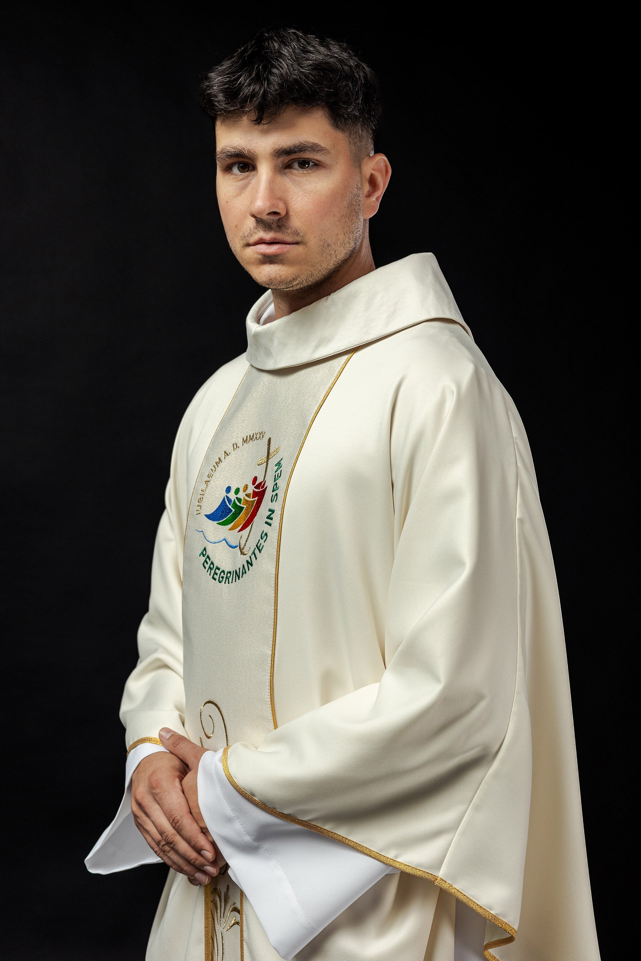 Casula creme com faixa bordada e logo do Jubileu Roma 2025