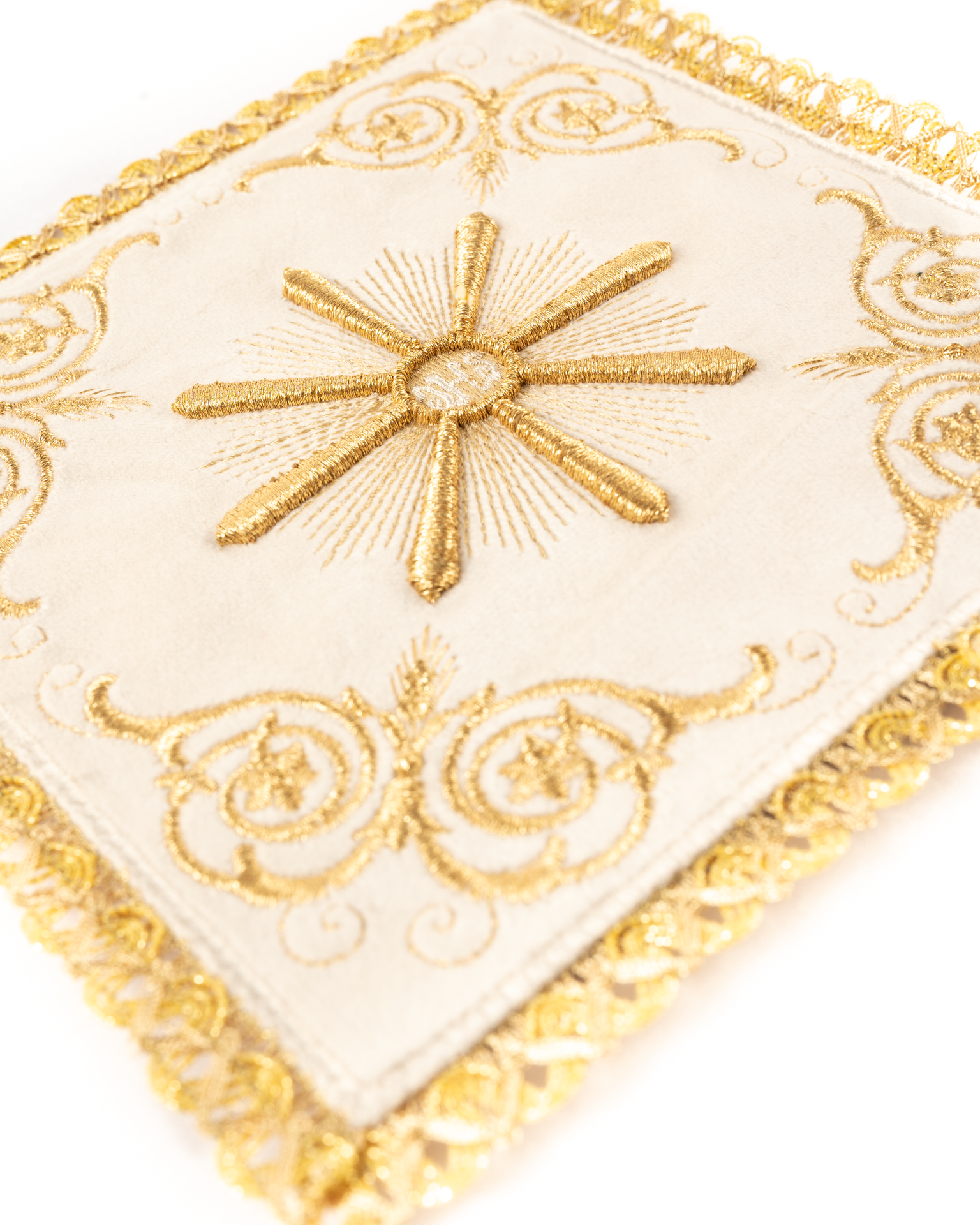 Conjunto de alfaias litúrgicas creme: pala de veludo com bordado do sol eucarístico sobre um cálice dourado, corporal branco com cruzes, sanguíneo e manutérgio.