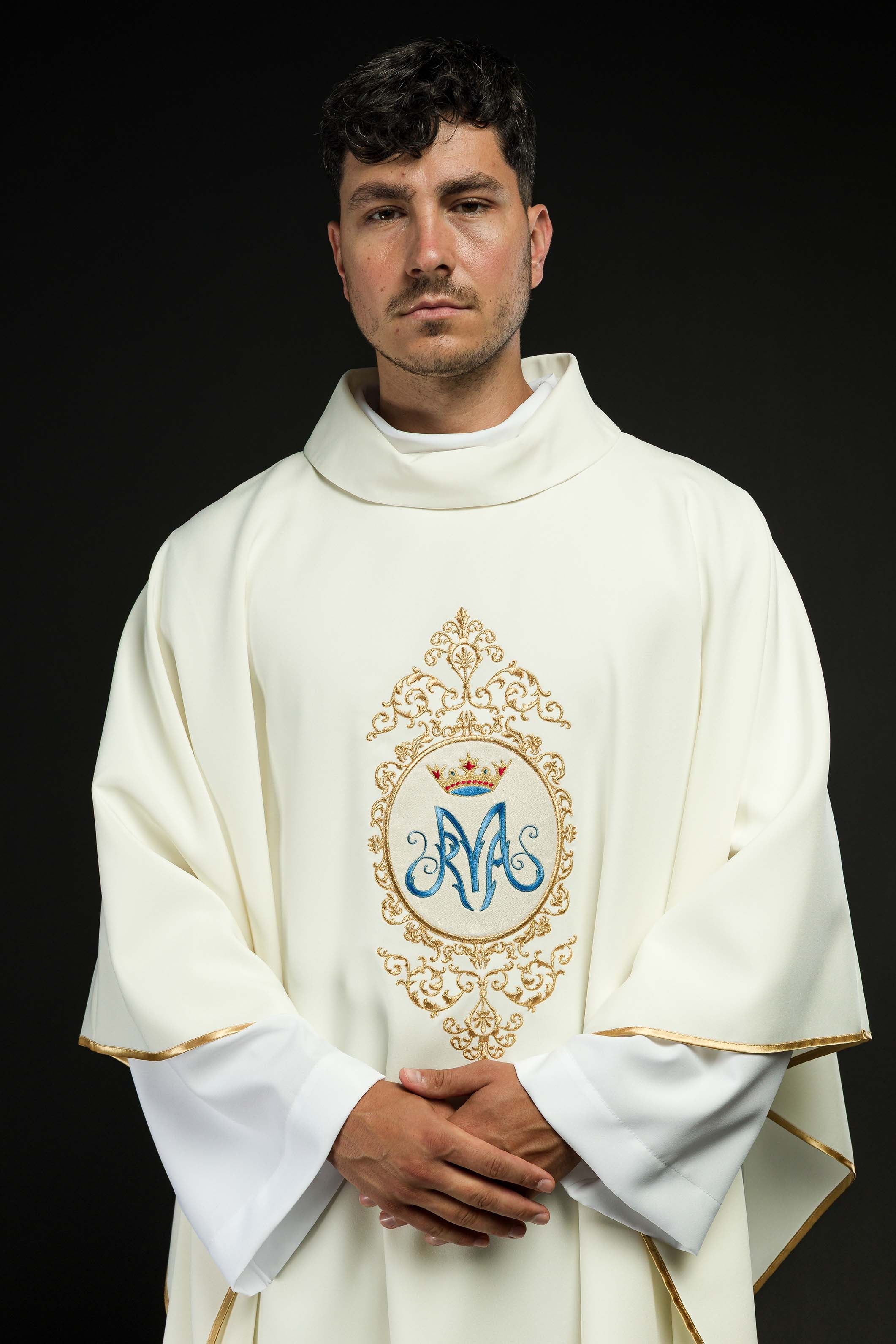 Casula com motivo mariano e bordado dourado, brasão mariano em dourado e azul, coroa dourada, gola alta.