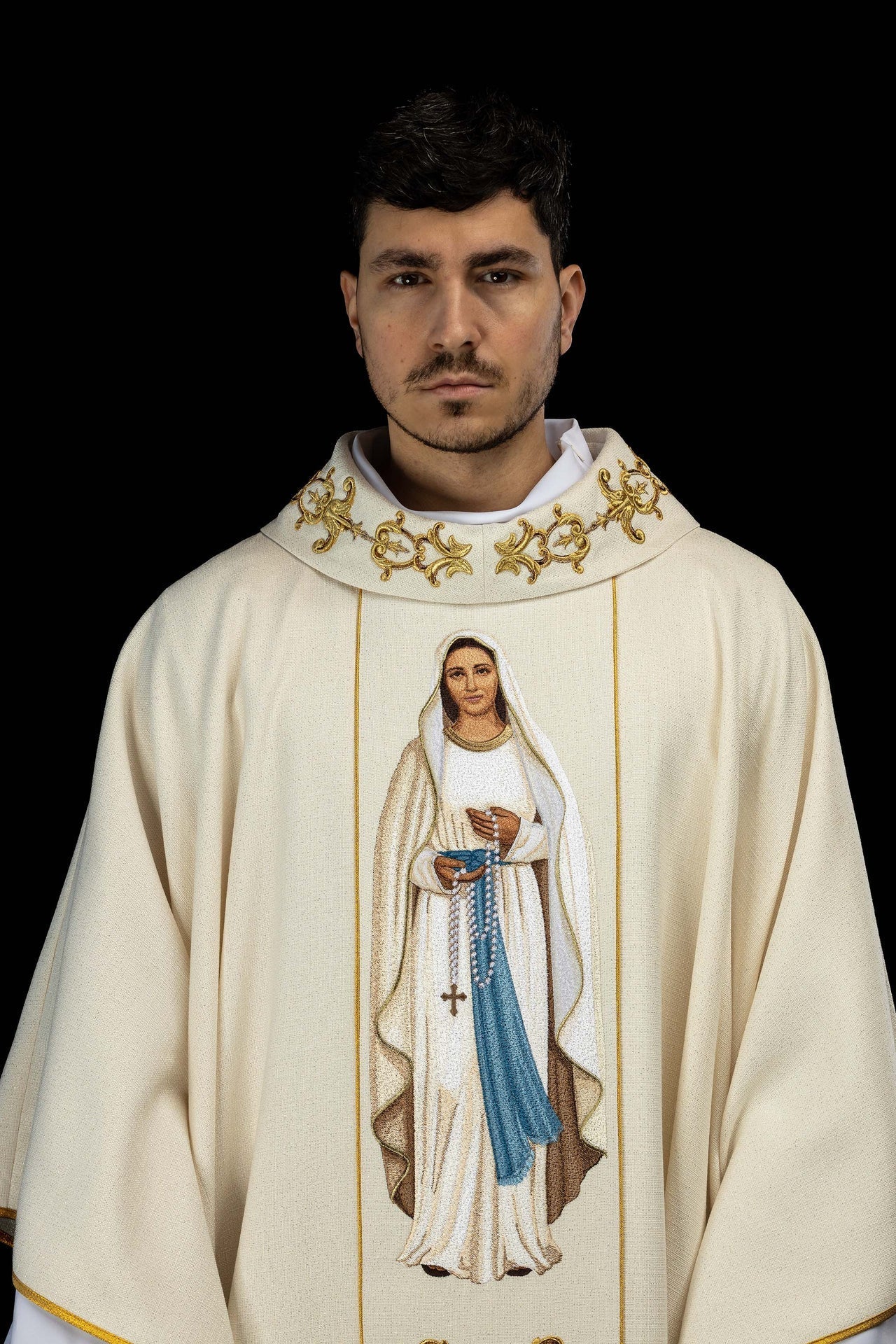 Casula creme com bordado de Nossa Senhora do Rosário e detalhes dourados.