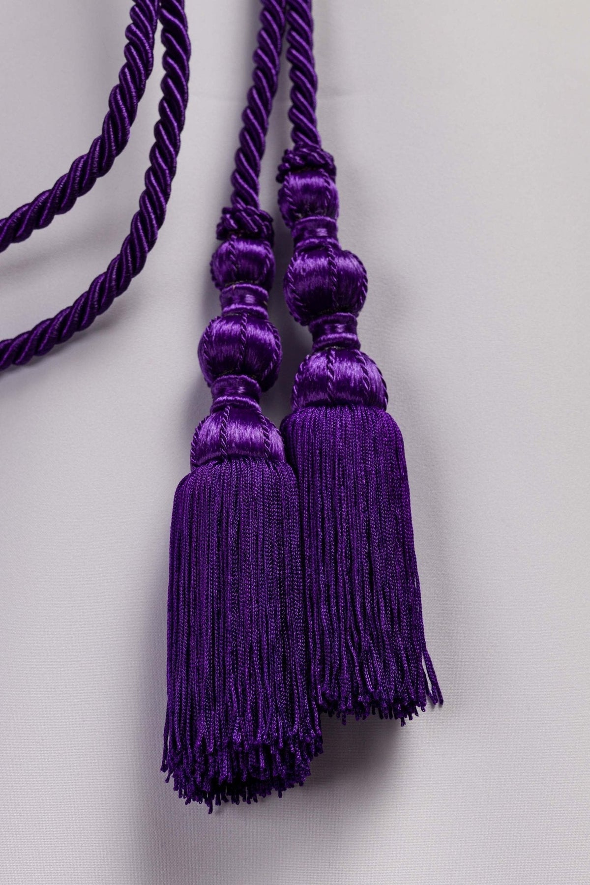 Cíngulo litúrgico roxo em close-up das duas borlas com franjas
