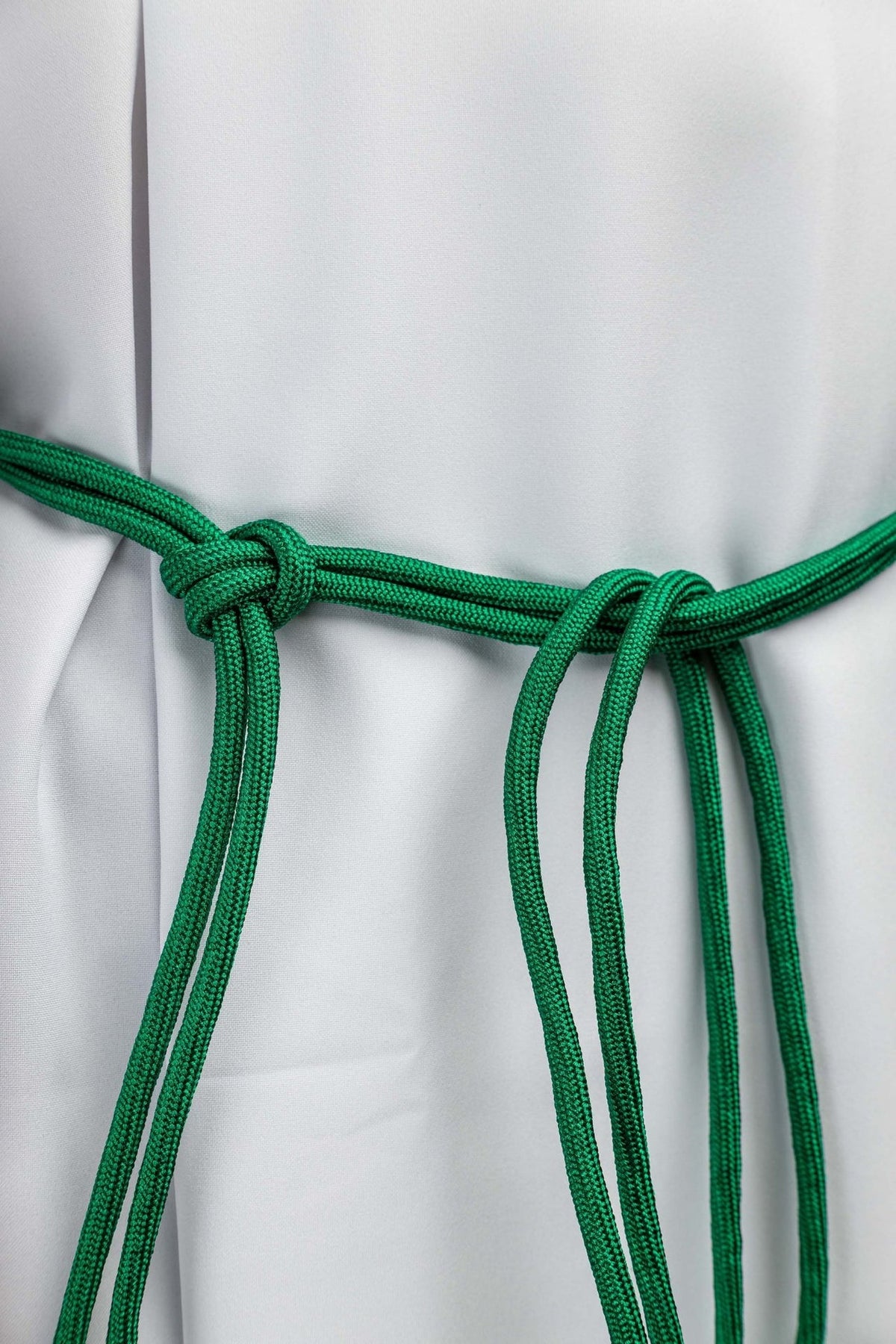 Cíngulo verde em close-up, mostrando o nó e os cordões trançados