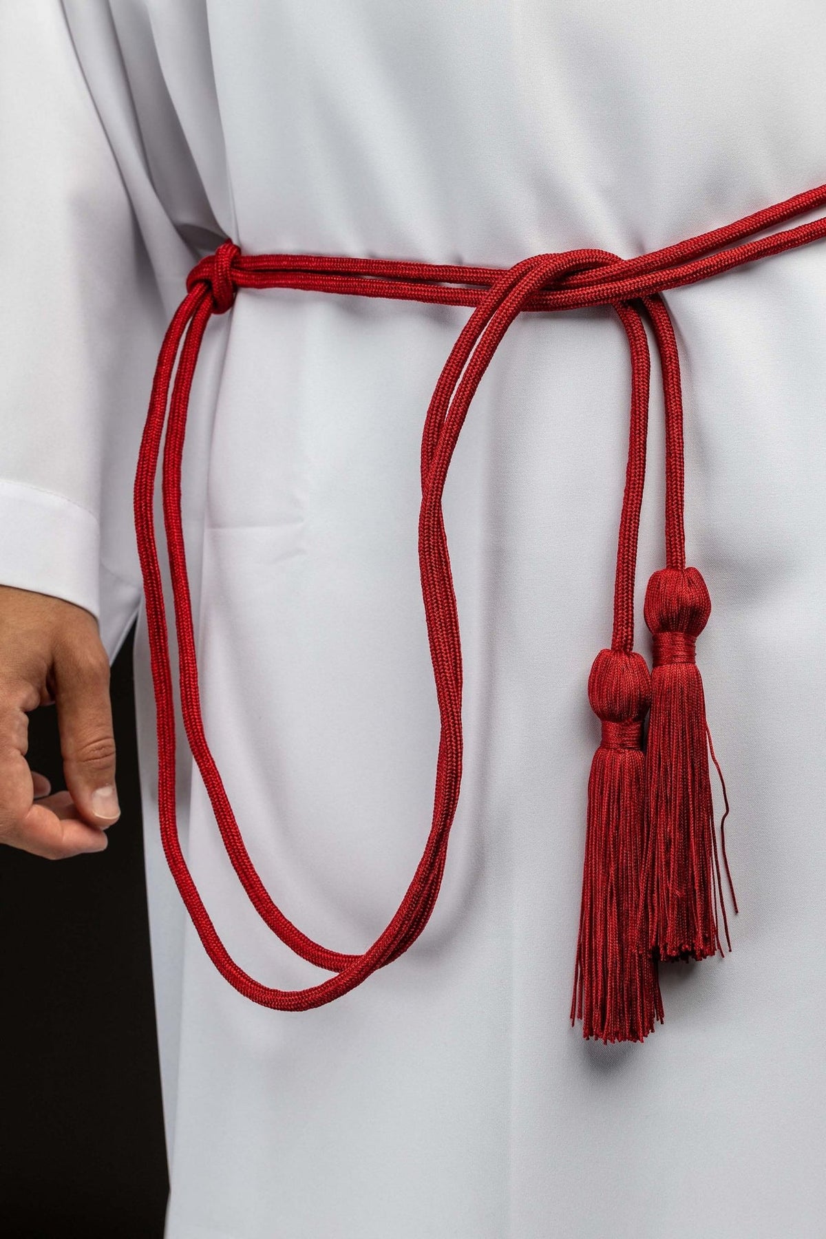 Cíngulo litúrgico vermelho com borlas decorativas, usado sobre alva branca, com cordão duplo e duas borlas