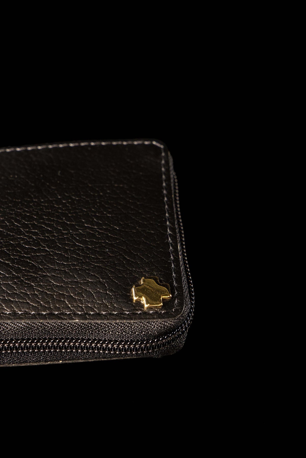 Bolsa litúrgica fechada em close-up, com textura preta e detalhe dourado