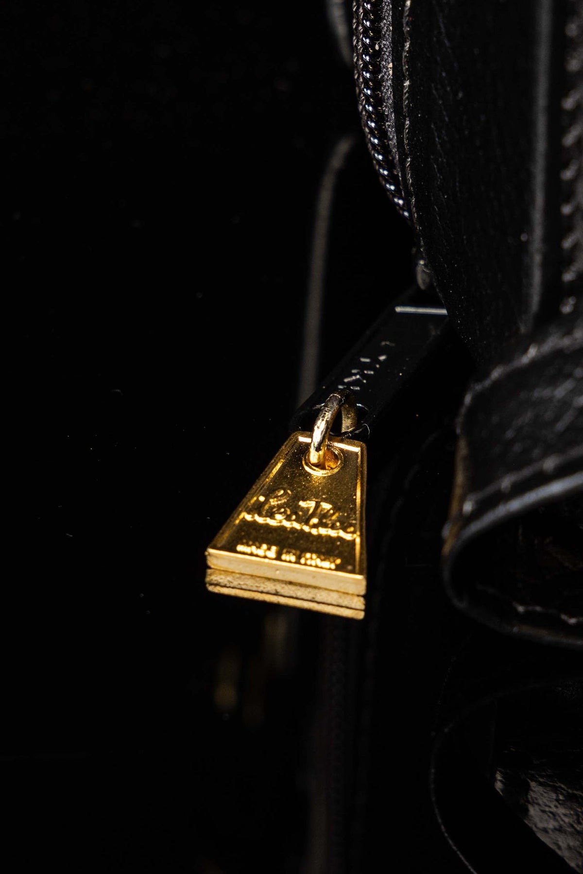 Detalhe da alça e do fecho dourado da maleta missionária preta