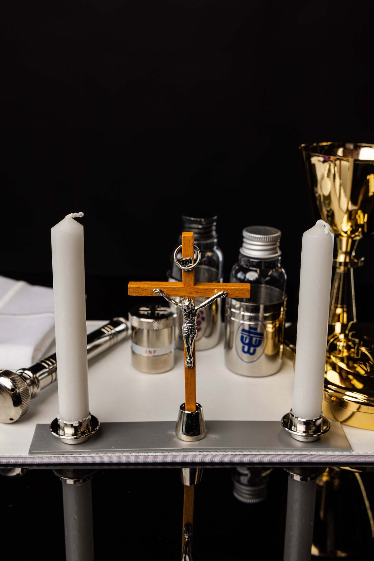 Equipamento litúrgico de alumínio com cruz, velas e recipientes metálicos