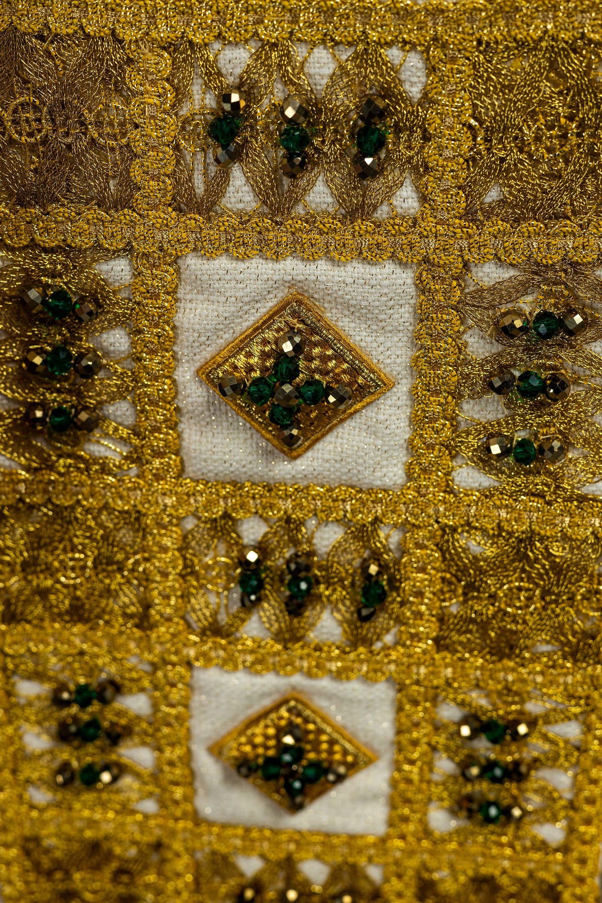 Estola com bordado dourado e pedras naturais verdes, close-up dos motivos geométricos