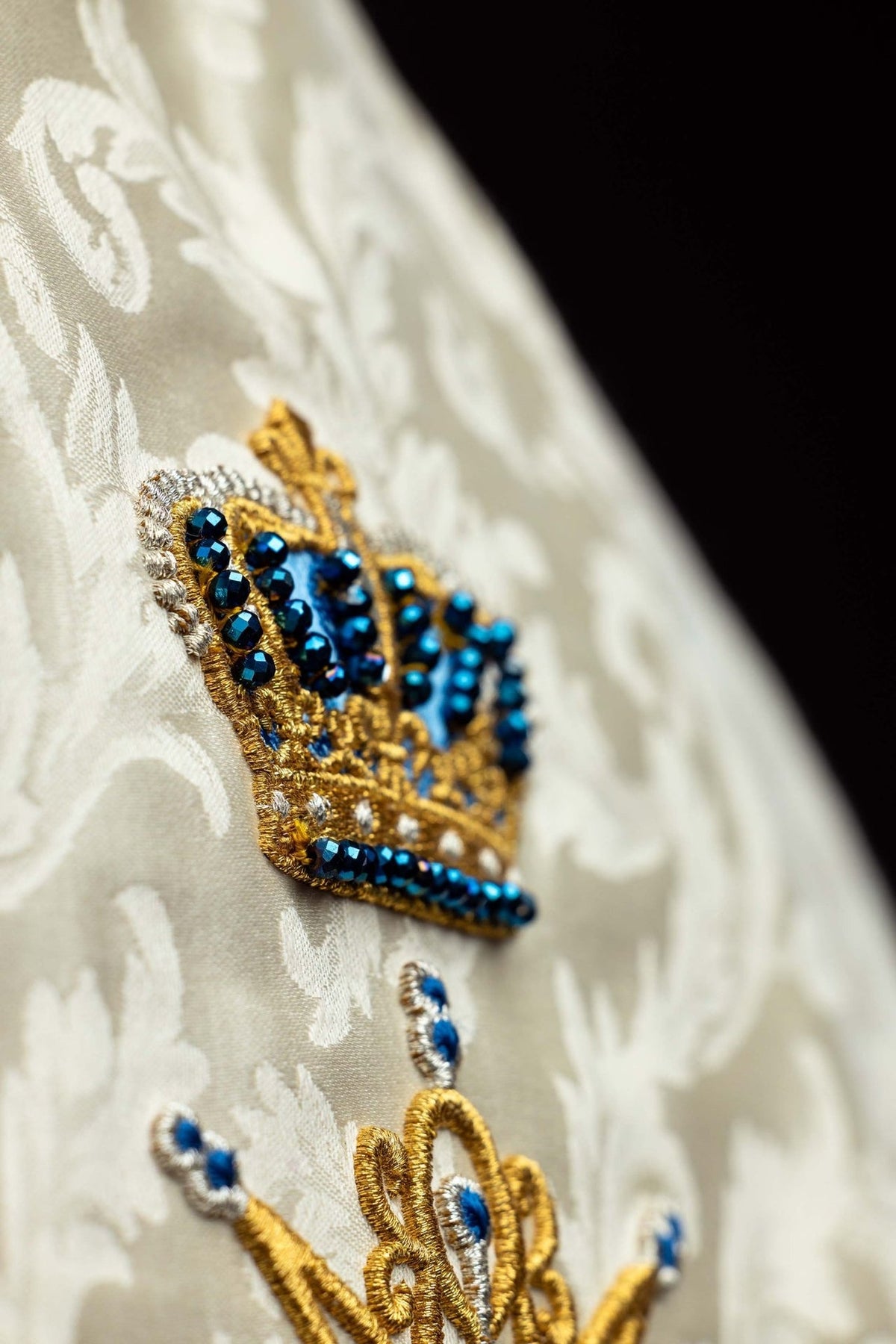 Capa de asperges litúrgica mariana marfim ecru em close-up, com bordado dourado e pedras azuis