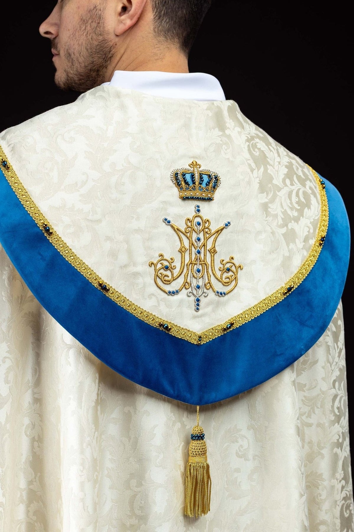 Capa de asperges litúrgica mariana vista pelas costas, com símbolo mariano bordado e faixa azul