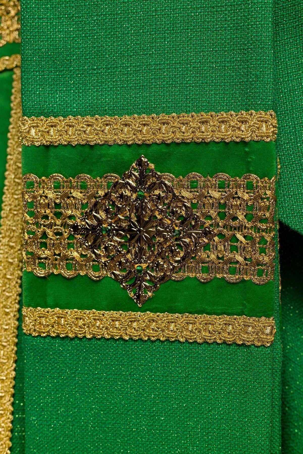 Casula verde artesanal mostrando o aplique lateral, franjas douradas e ornamentos centrais