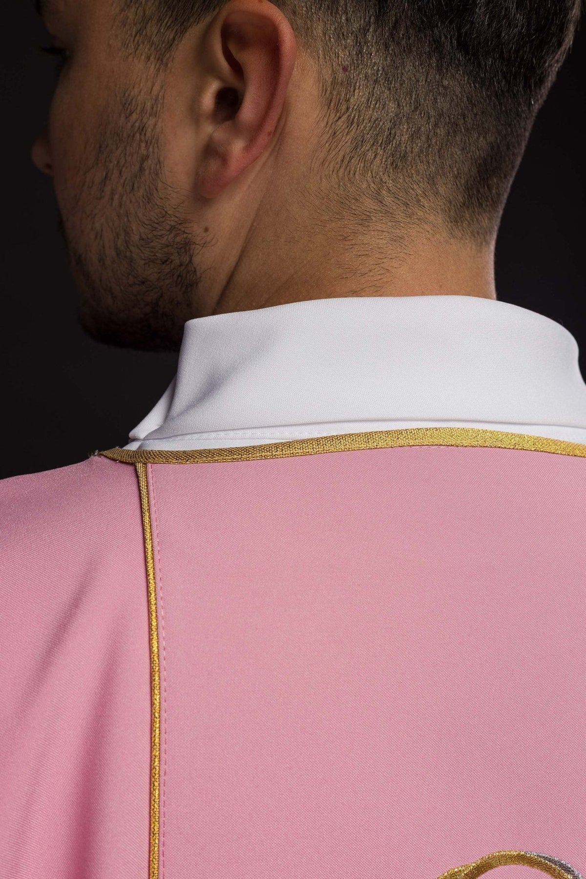 Dalmática rosa, vista posterior próxima com gola branca e acabamento dourado