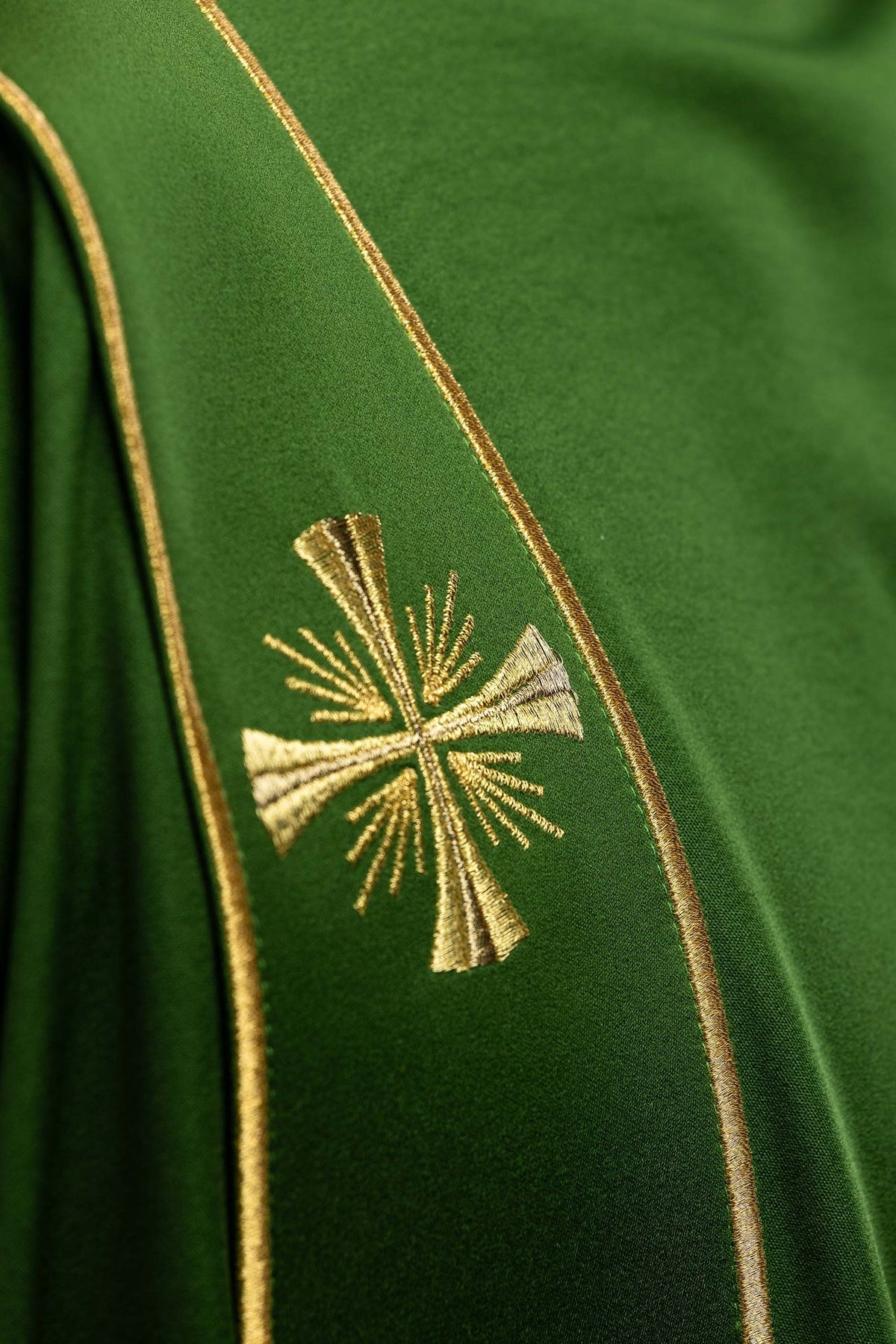 Dalmática verde com cruz dourada bordada e faixa com acabamento dourado em close-up