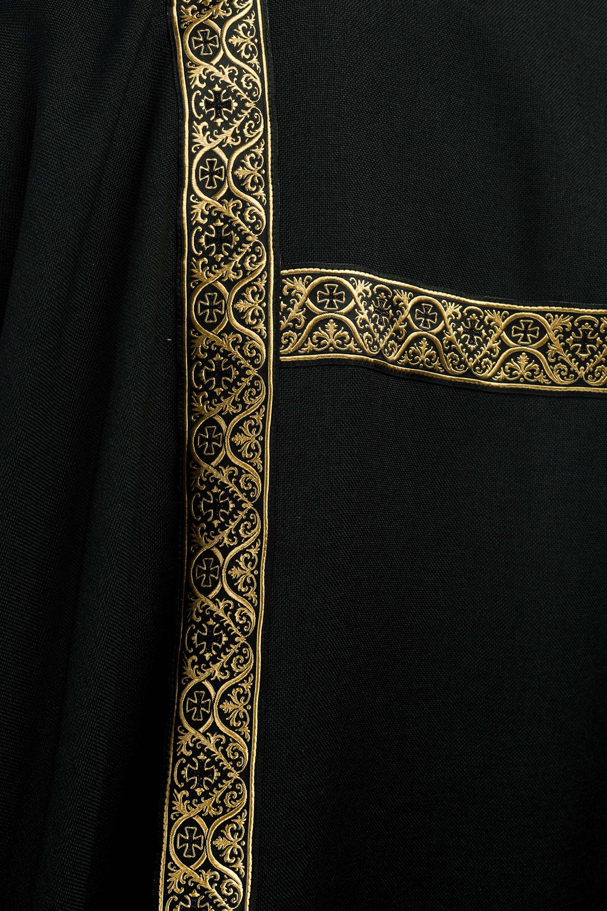 Dalmática preta com faixas de brocado dourado, detalhe frontal do brocado dourado
