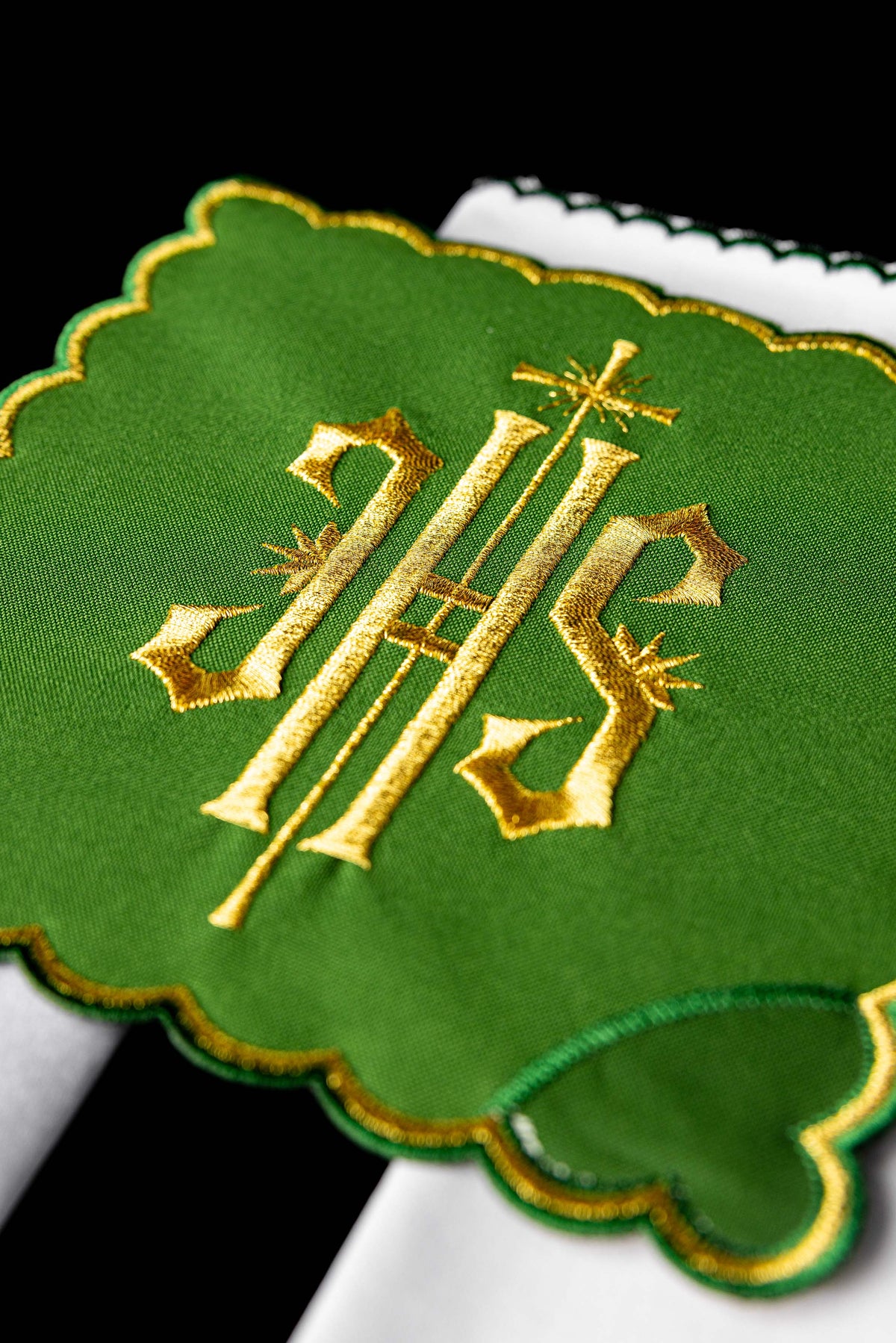 Conjunto de alfaias litúrgicas com detalhe aproximado do IHS dourado bordado em tecido verde