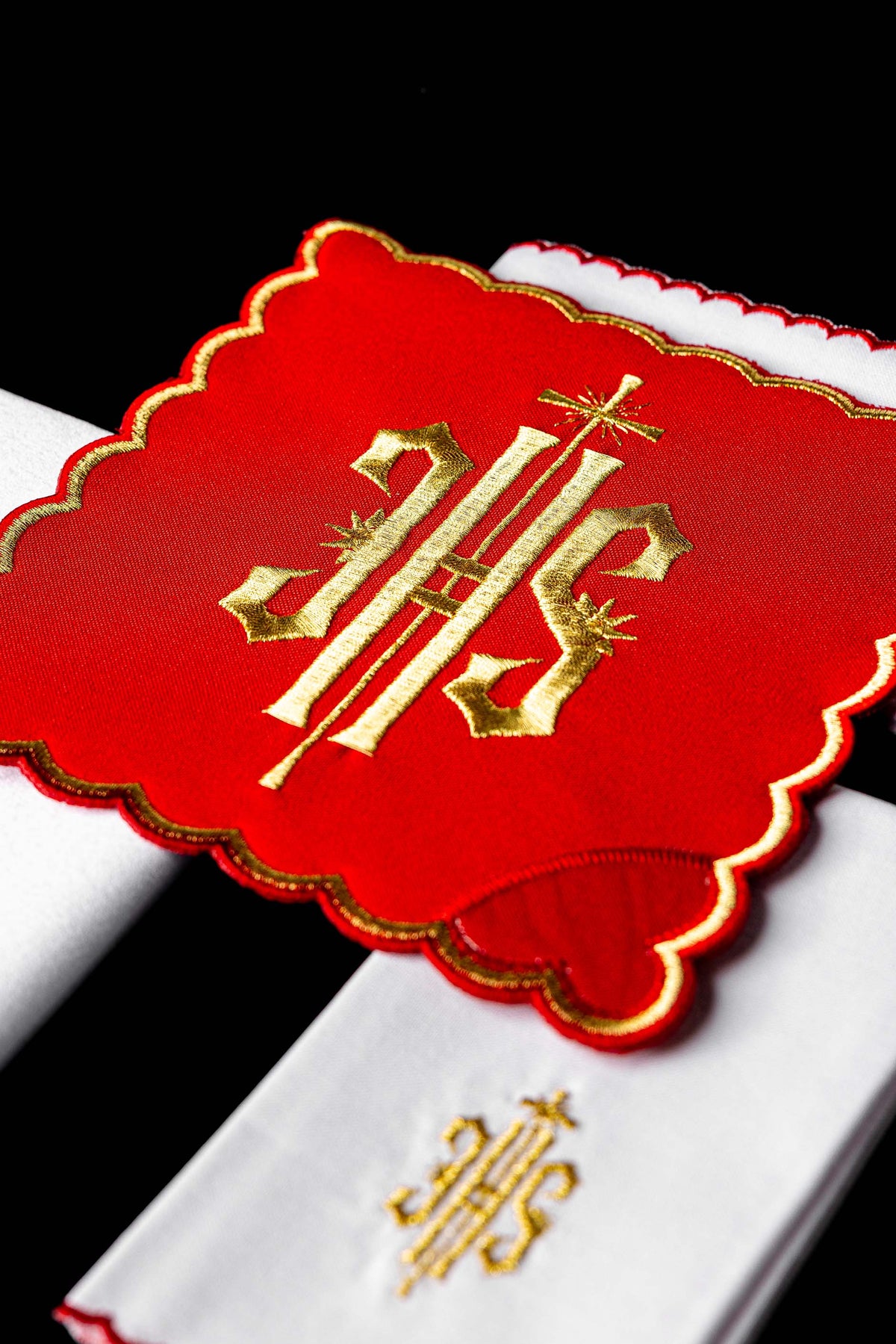 Conjunto de alfaias litúrgicas com close-up do IHS dourado bordado em peça vermelha