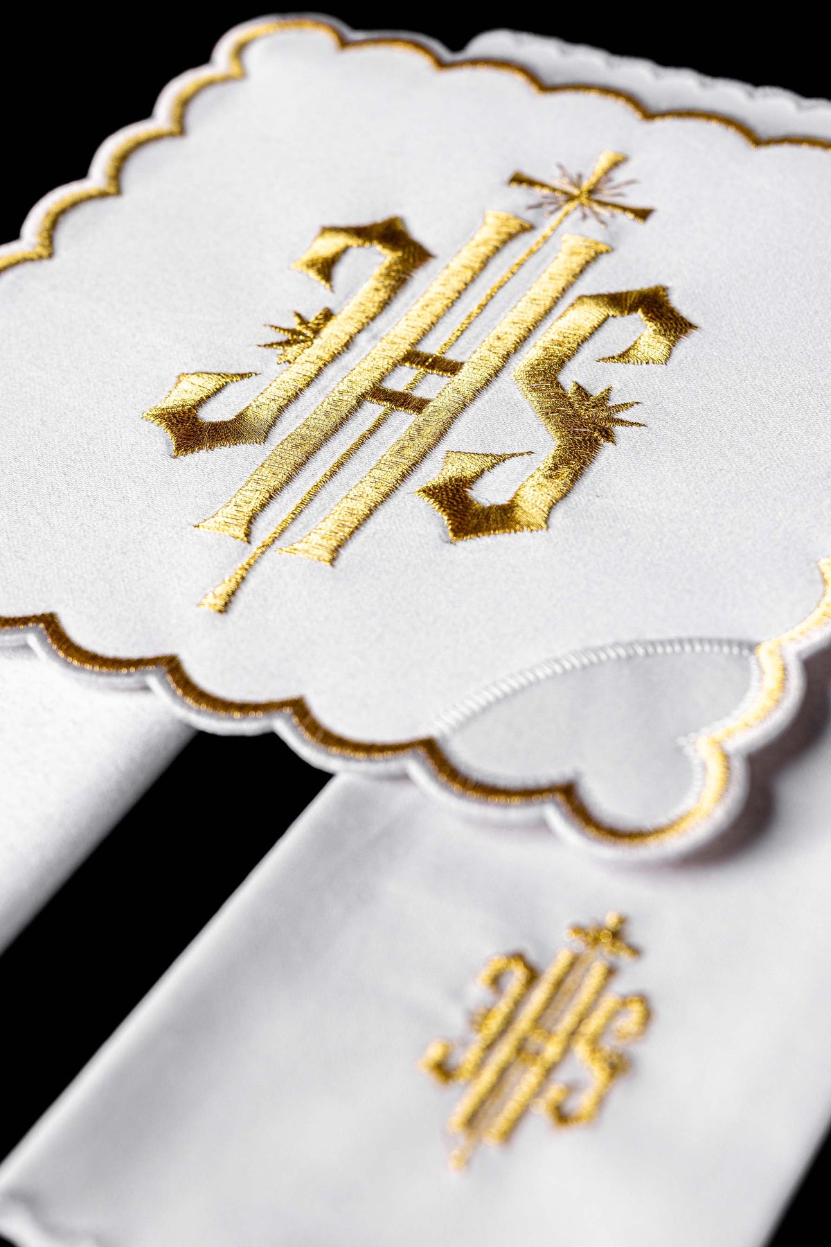 Conjunto de alfaias litúrgicas com monograma IHS bordado em dourado, close-up