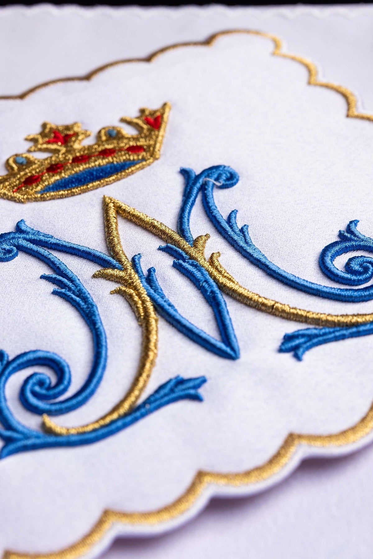 Close-up do bordado mariano azul e dourado com coroa nas alfaias litúrgicas