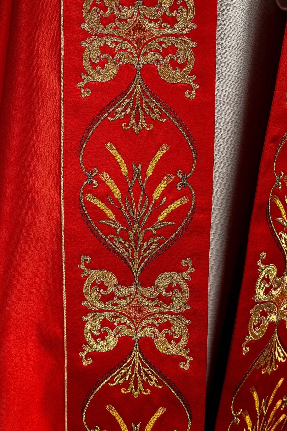 Capa de asperges vermelha em detalhe do bordado frontal com espigas e arabescos dourados
