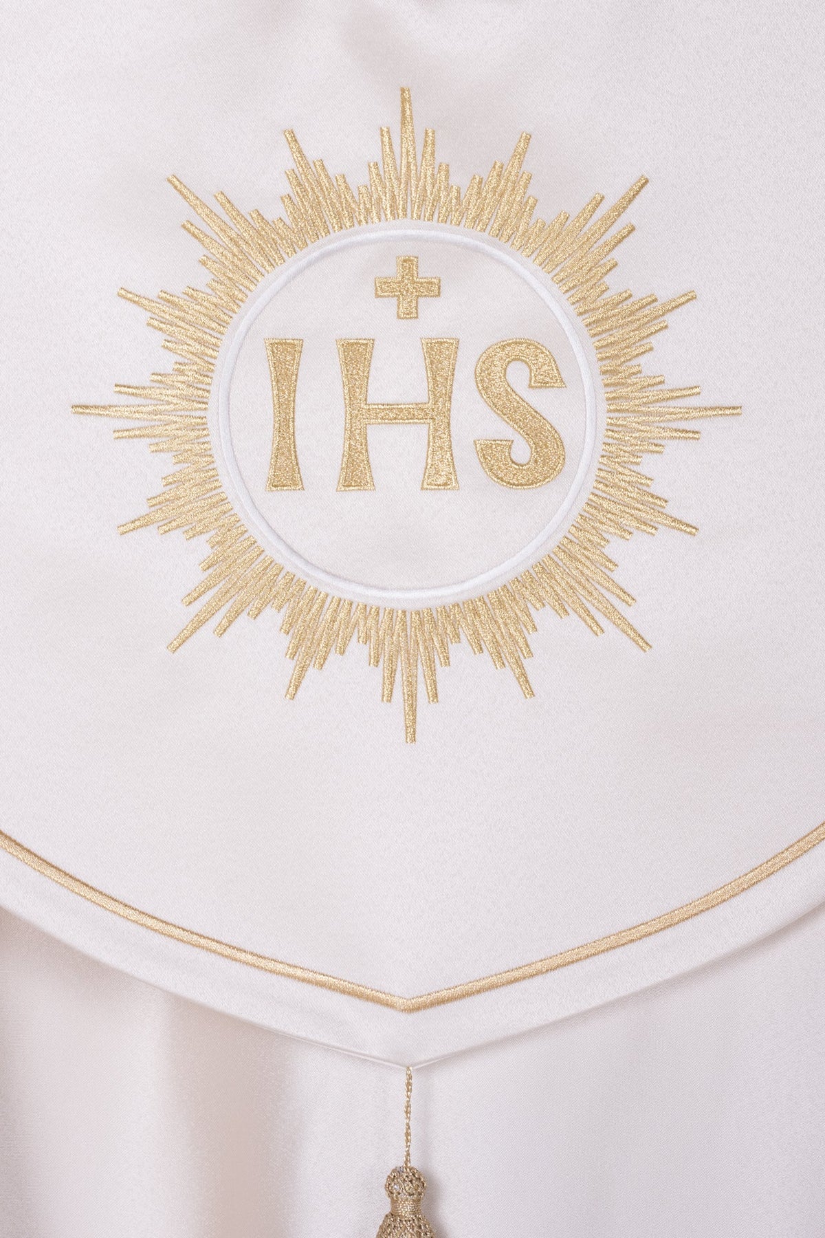 Capa de asperges com close-up do bordado IHS dourado e acabamento em marfim ecru