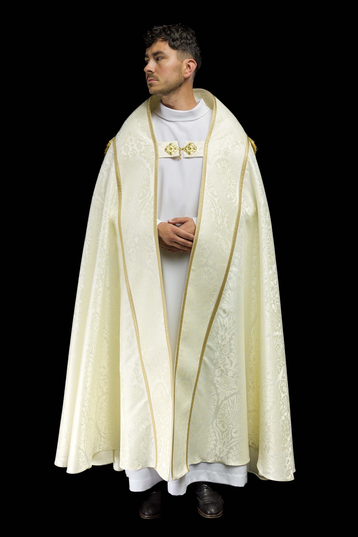Capa de asperges romana lisa em jacquard creme vista de frente, com galão dourado e fecho ornamental