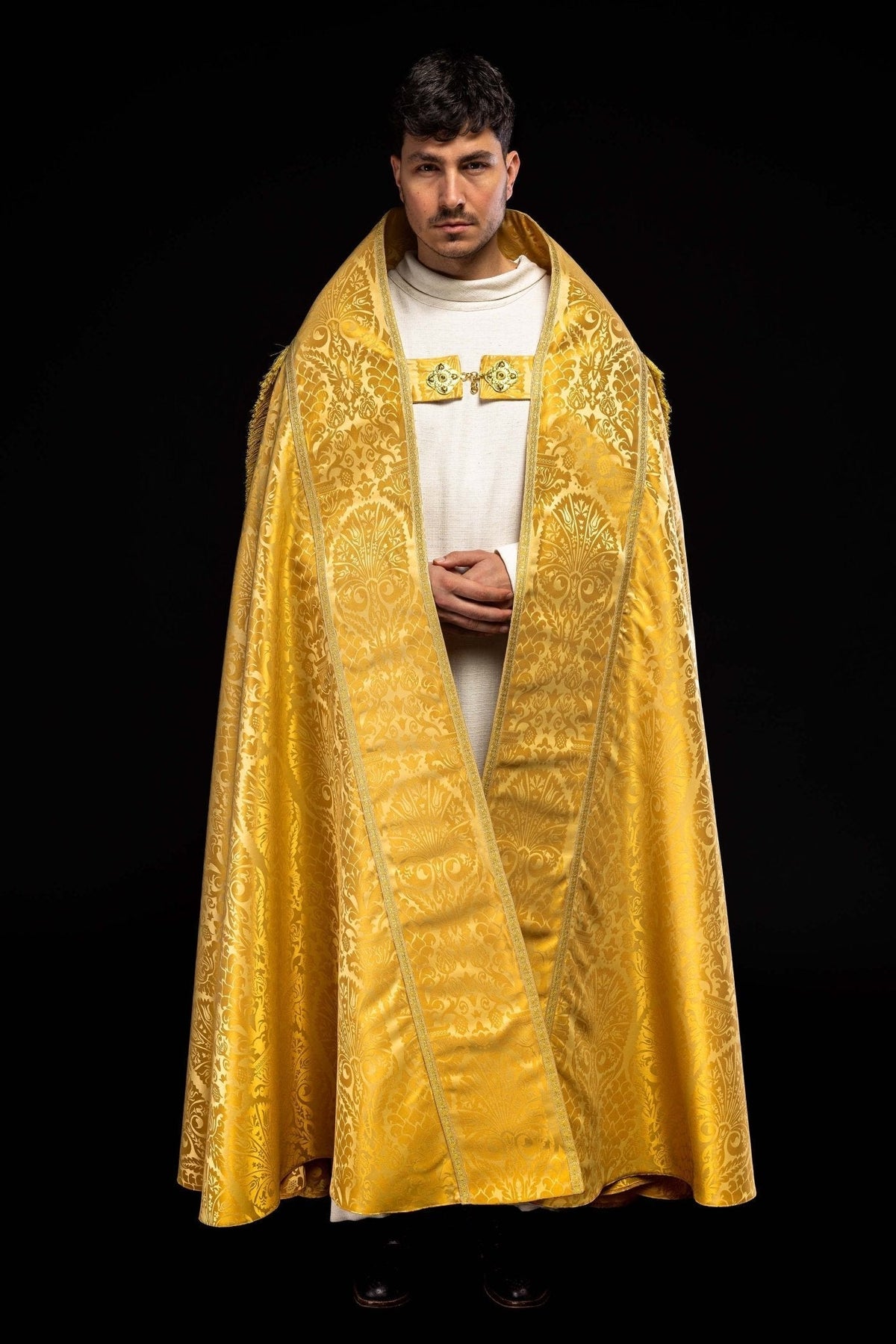 Capa de asperges romana lisa em jacquard dourada, vista frontal com estola e fecho ornamentado