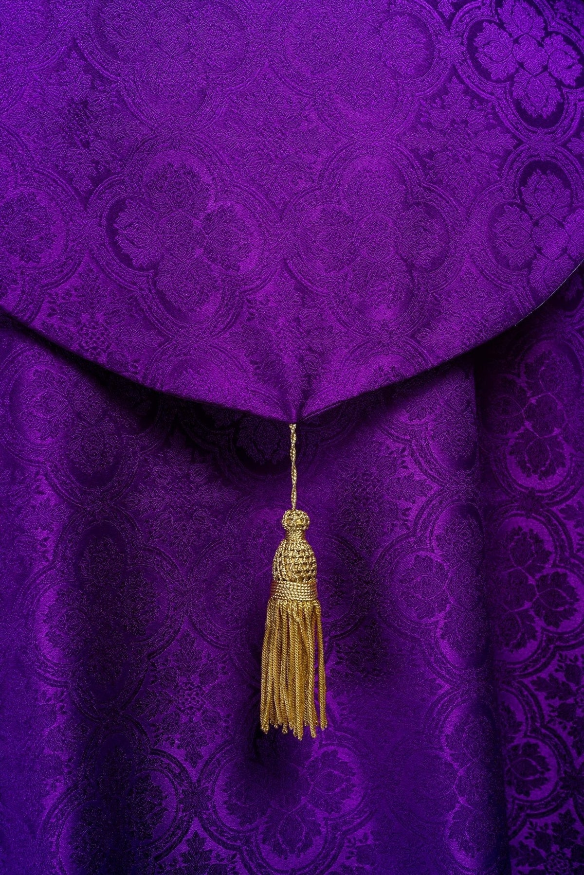 Capa de asperges jacquard roxa em close-up da pala e do pingente dourado