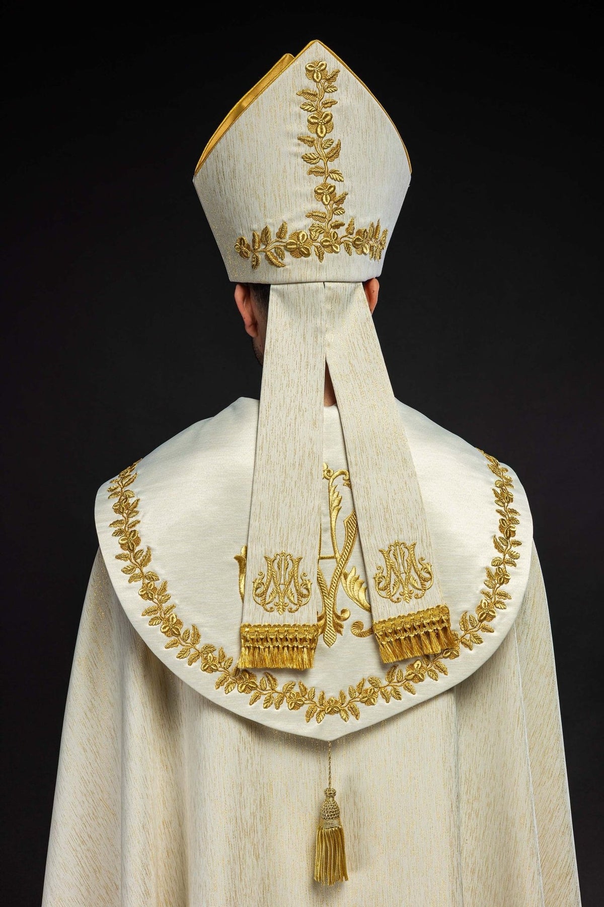 Mitra vista pelas costas, com bordado floral dourado e duas faixas longas