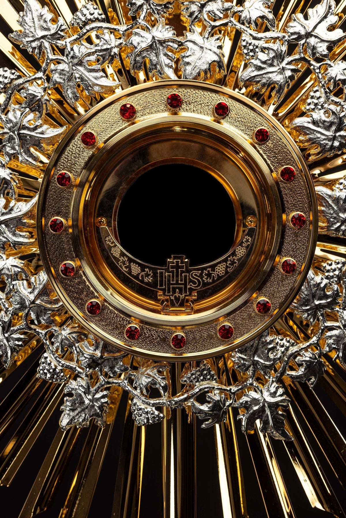 Ostensório dourado com rubis, close-up do aro com pedras vermelhas e monograma IHS