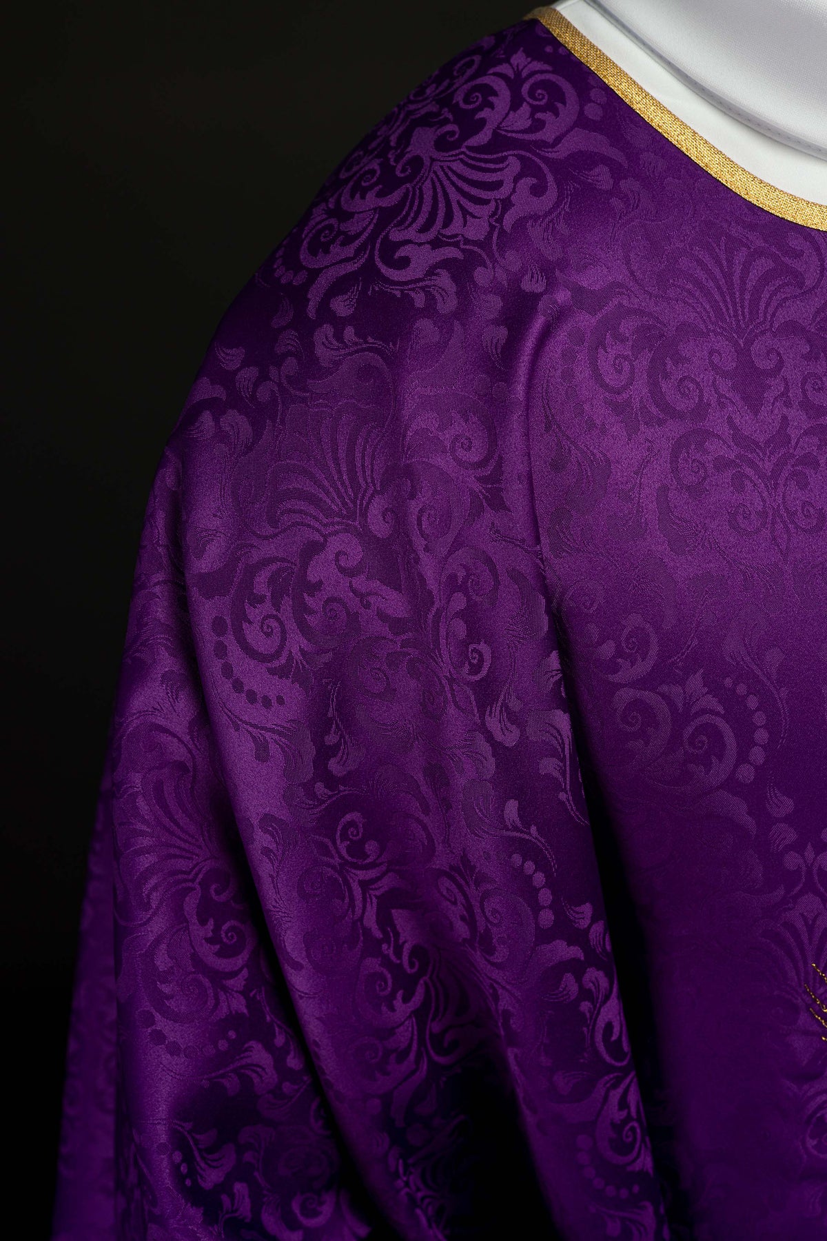 Casula roxa em detalhe da manga ampla com acabamento dourado e tecido jacquard