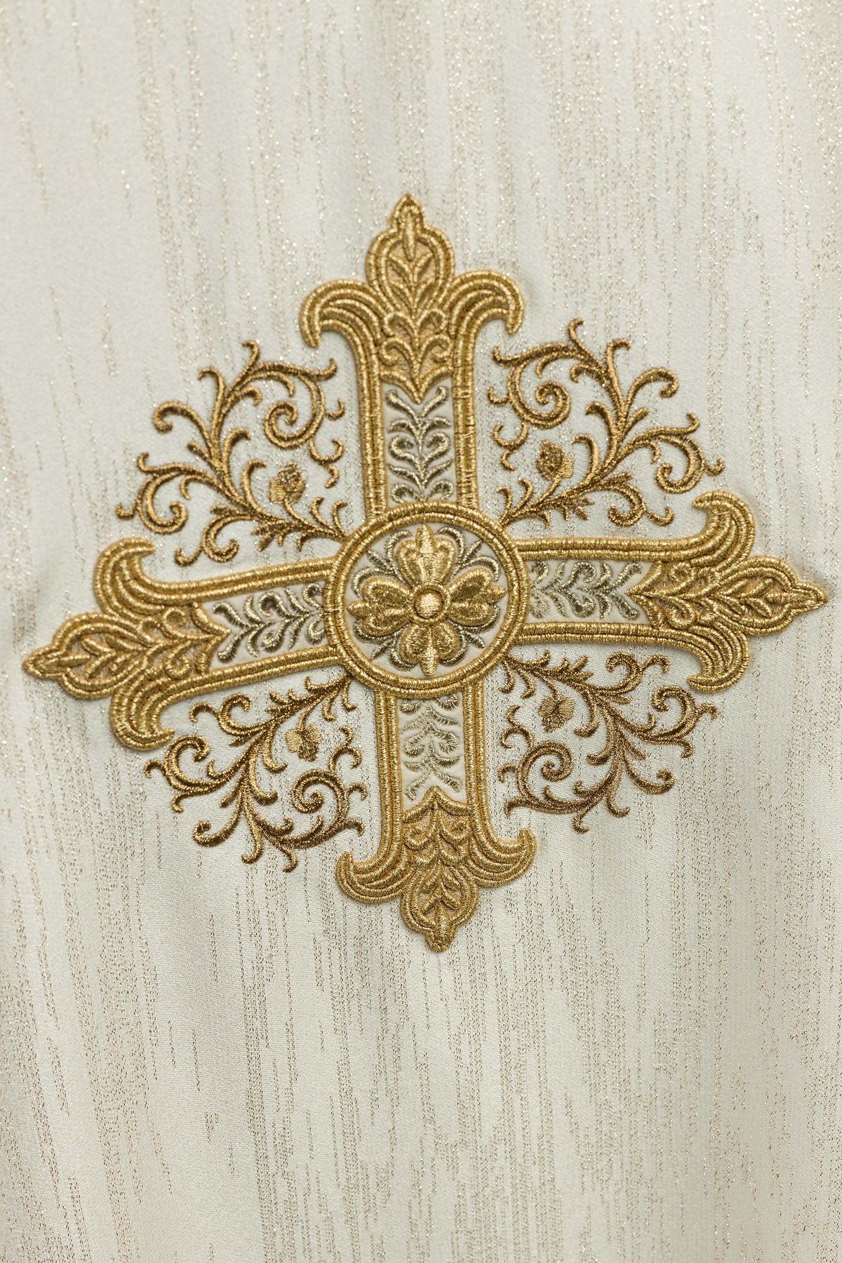 Casula creme, close da cruz ornamental bordada em dourado sobre tecido decorativo