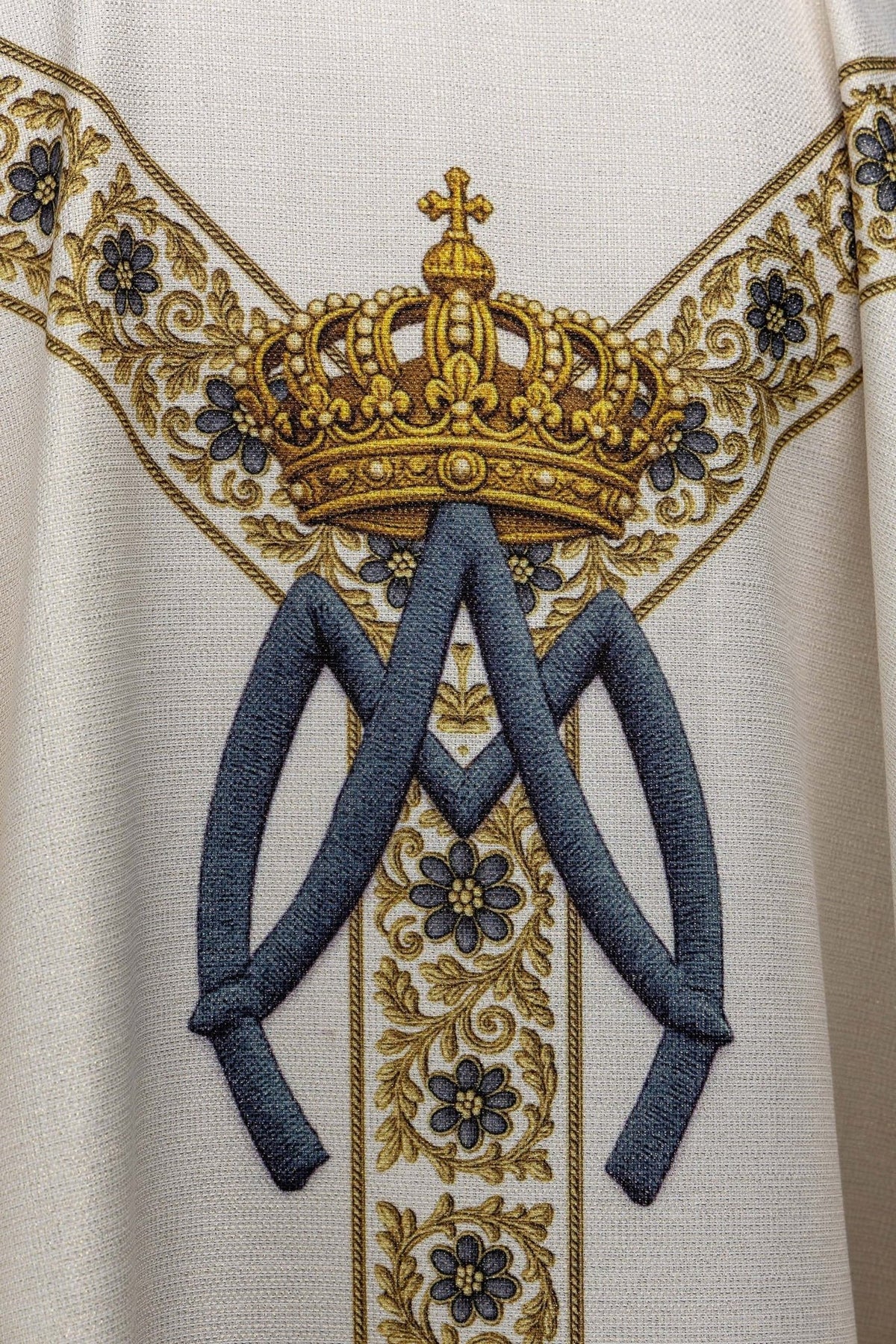 Casula mariana em close-up do símbolo mariano com coroa e laços azuis