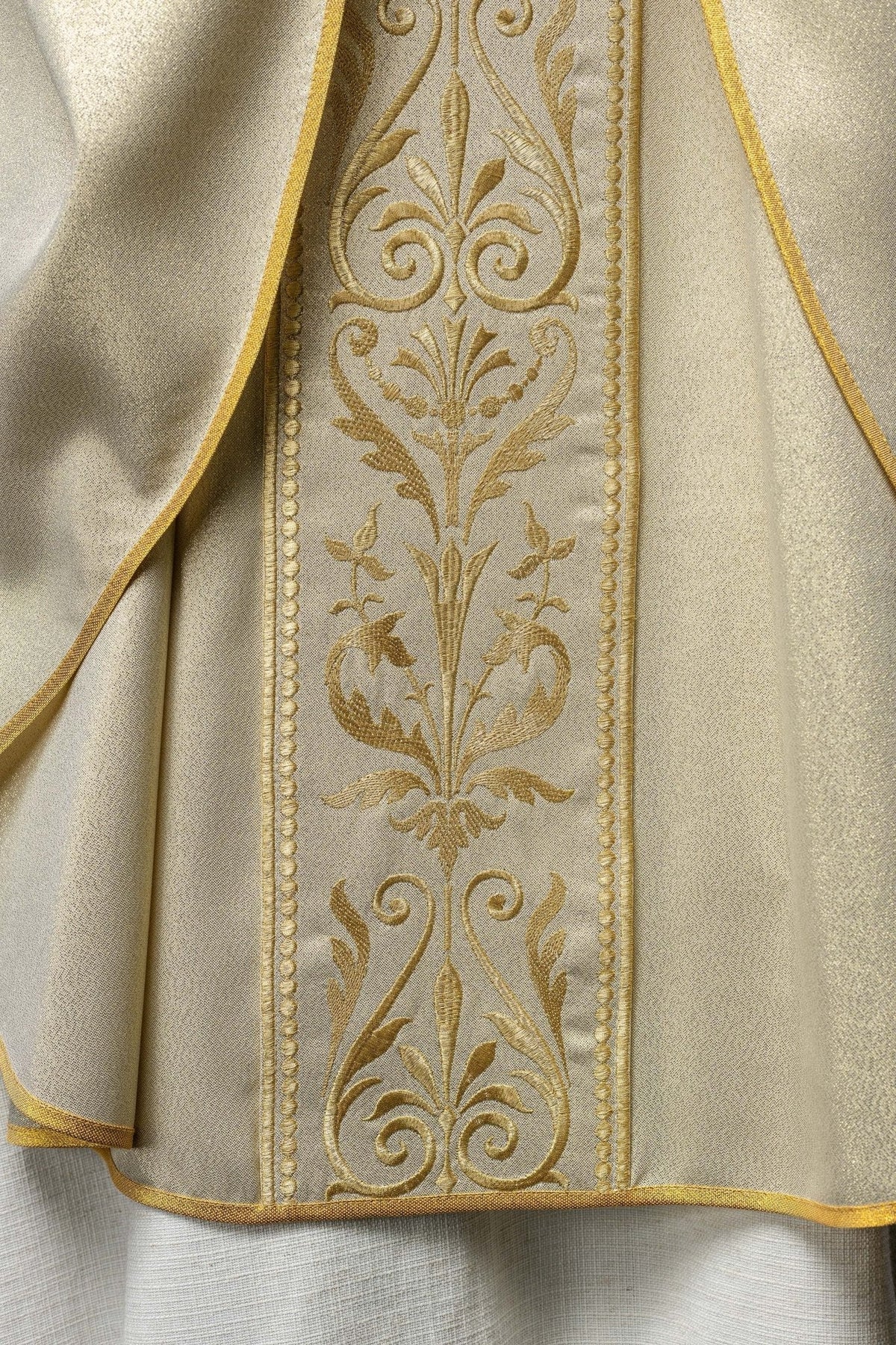Casula litúrgica vista frontal inferior, com faixa dourada bordada e barra com acabamento dourado
