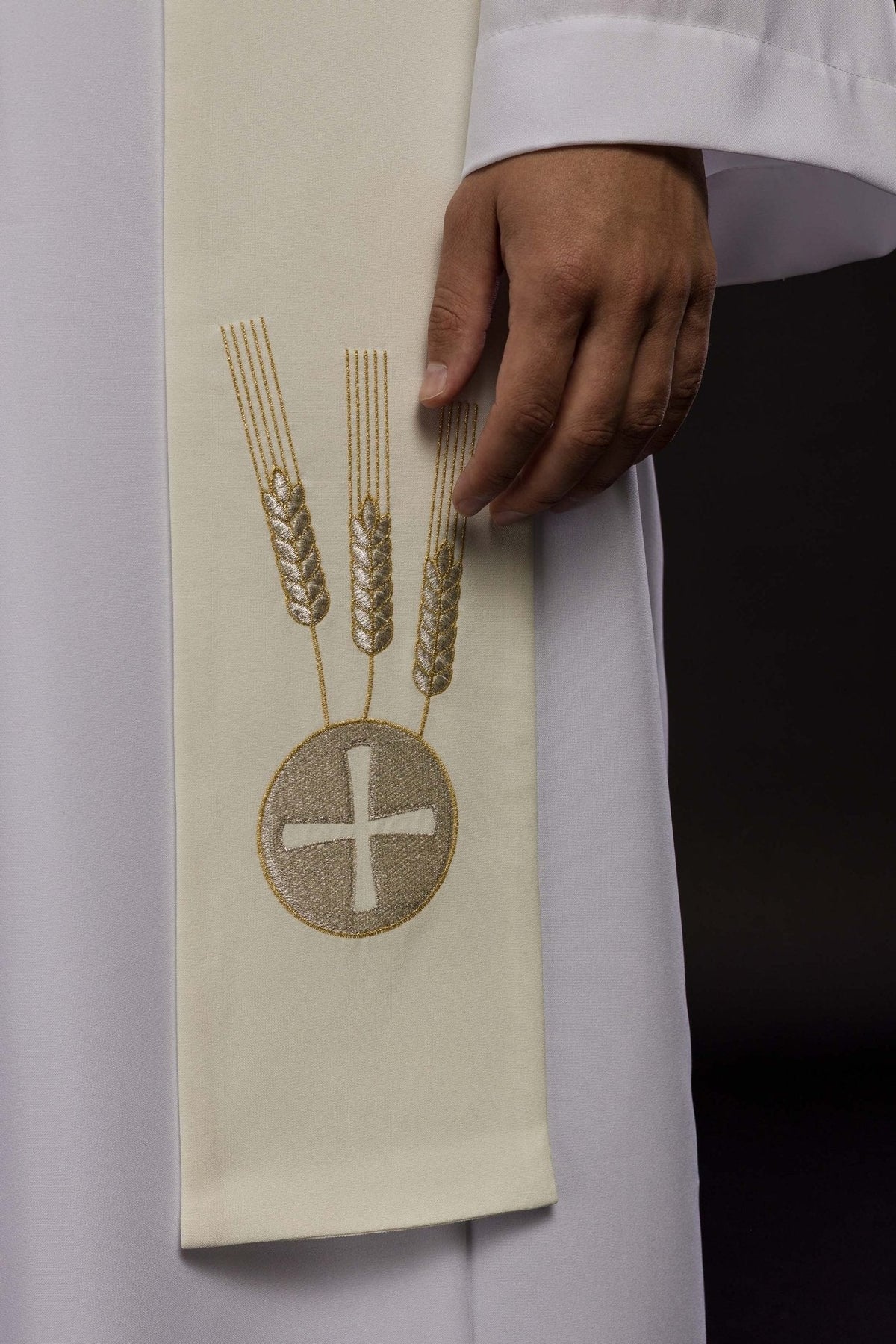 Estola creme em close-up, com três espigas e medalhão com cruz bordados
