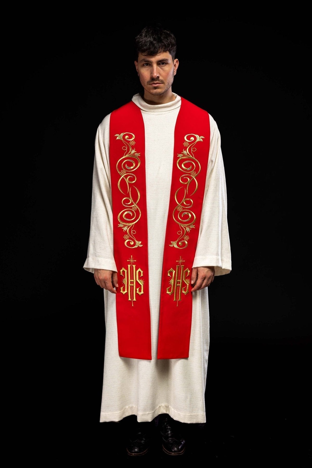 Estola sacerdotal bordada IHS vermelha vista de frente, usada, com arabescos dourados e símbolos IHS