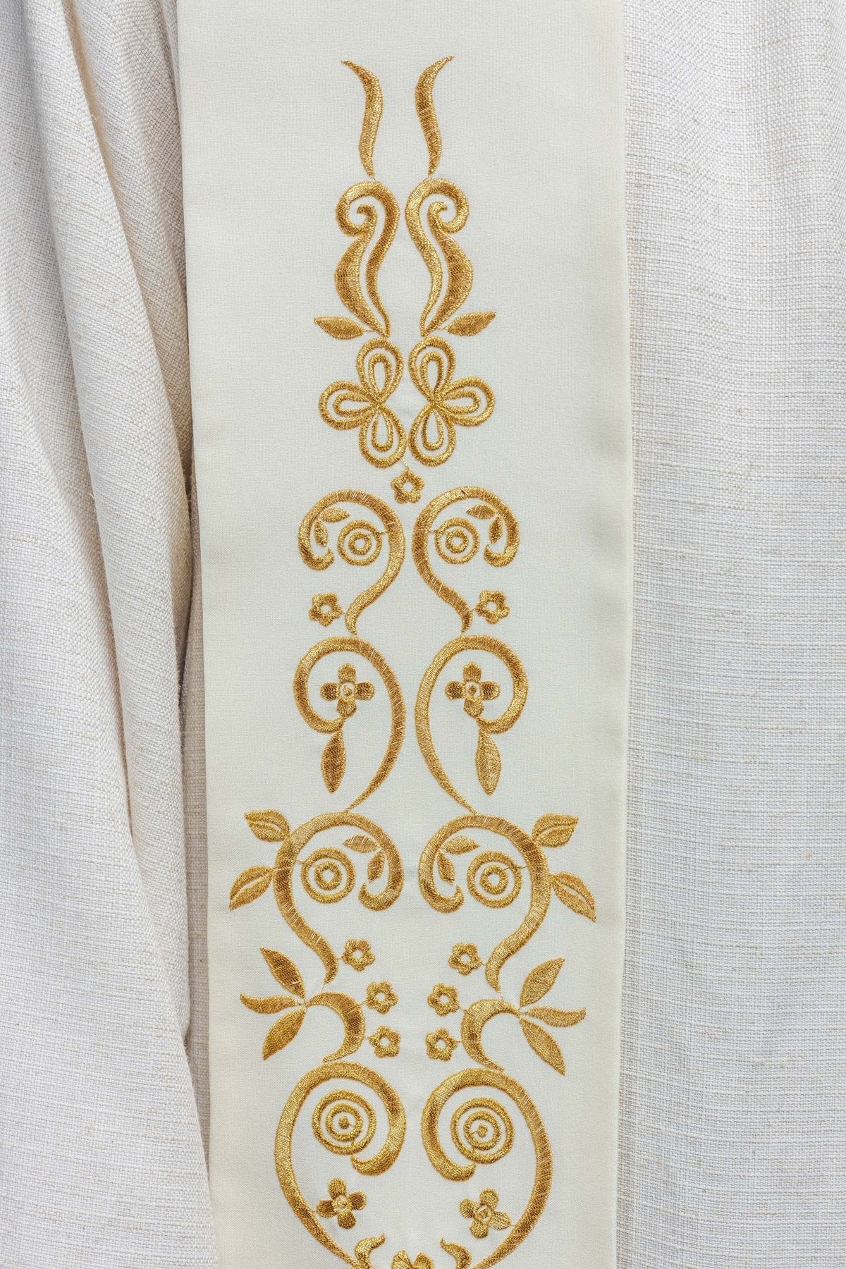 Estola mariana creme em close-up do bordado ornamental dourado com arabescos e flores