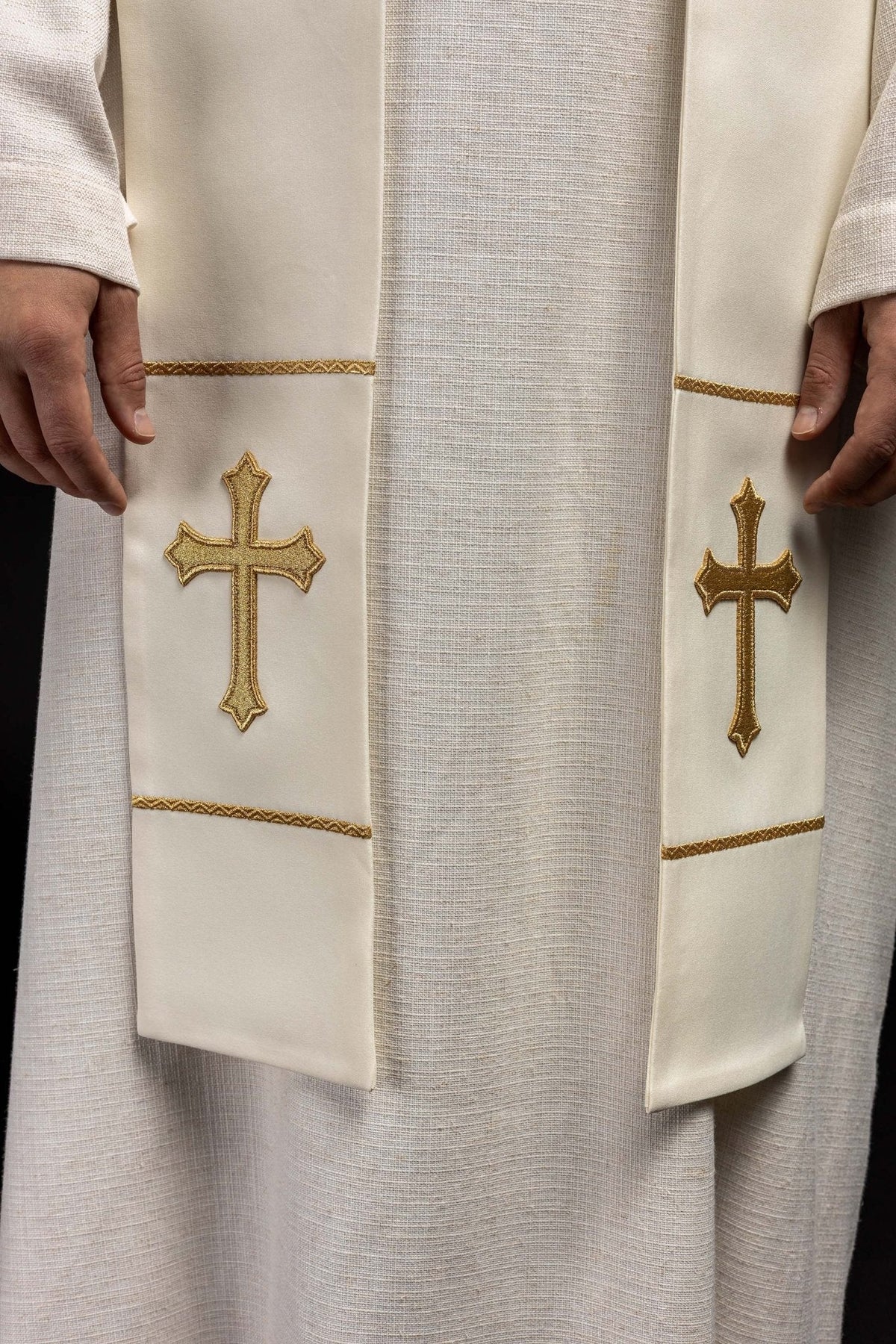 Estola sacerdotal creme em close-up, com duas cruzes douradas e acabamento dourado