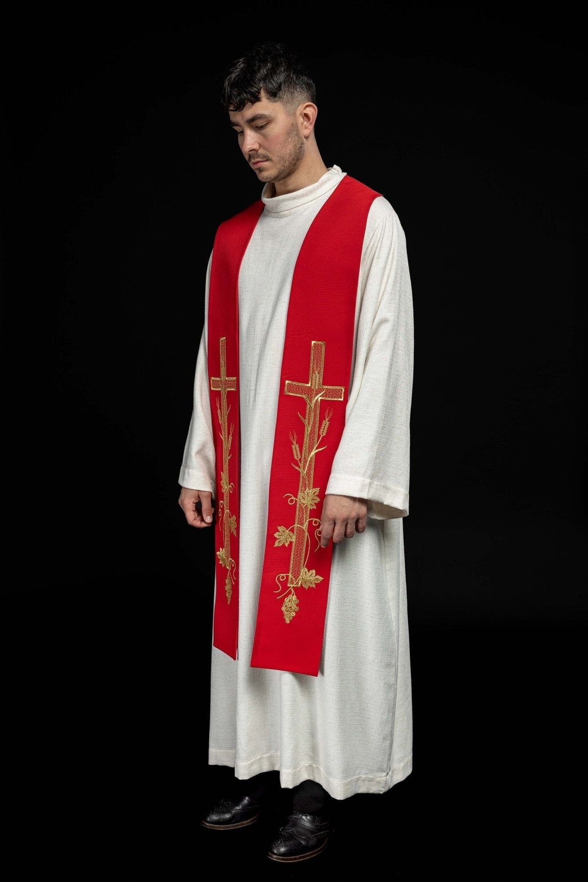 Estola sacerdotal vermelha usada em vista lateral, com bordados dourados de Cruz e ramos