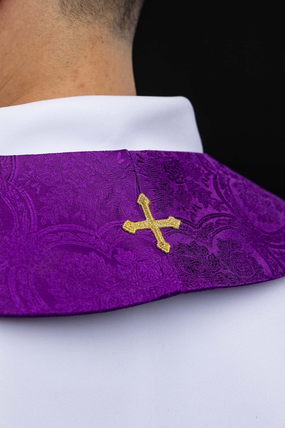 Estola sacerdotal roxa em tecido jacquard, close-up da cruz dourada junto ao pescoço