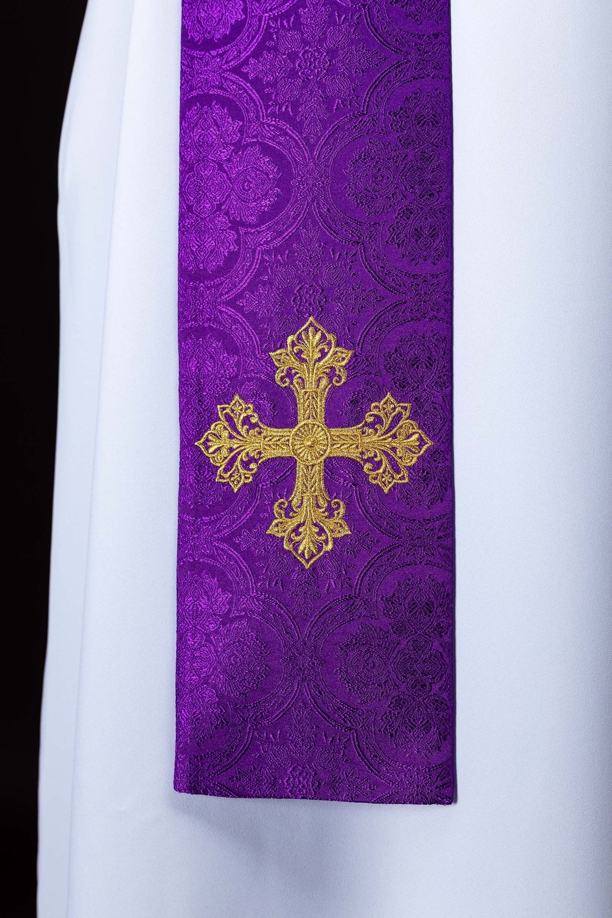 Estola roxa com cruz dourada bordada e tecido jacquard em close-up