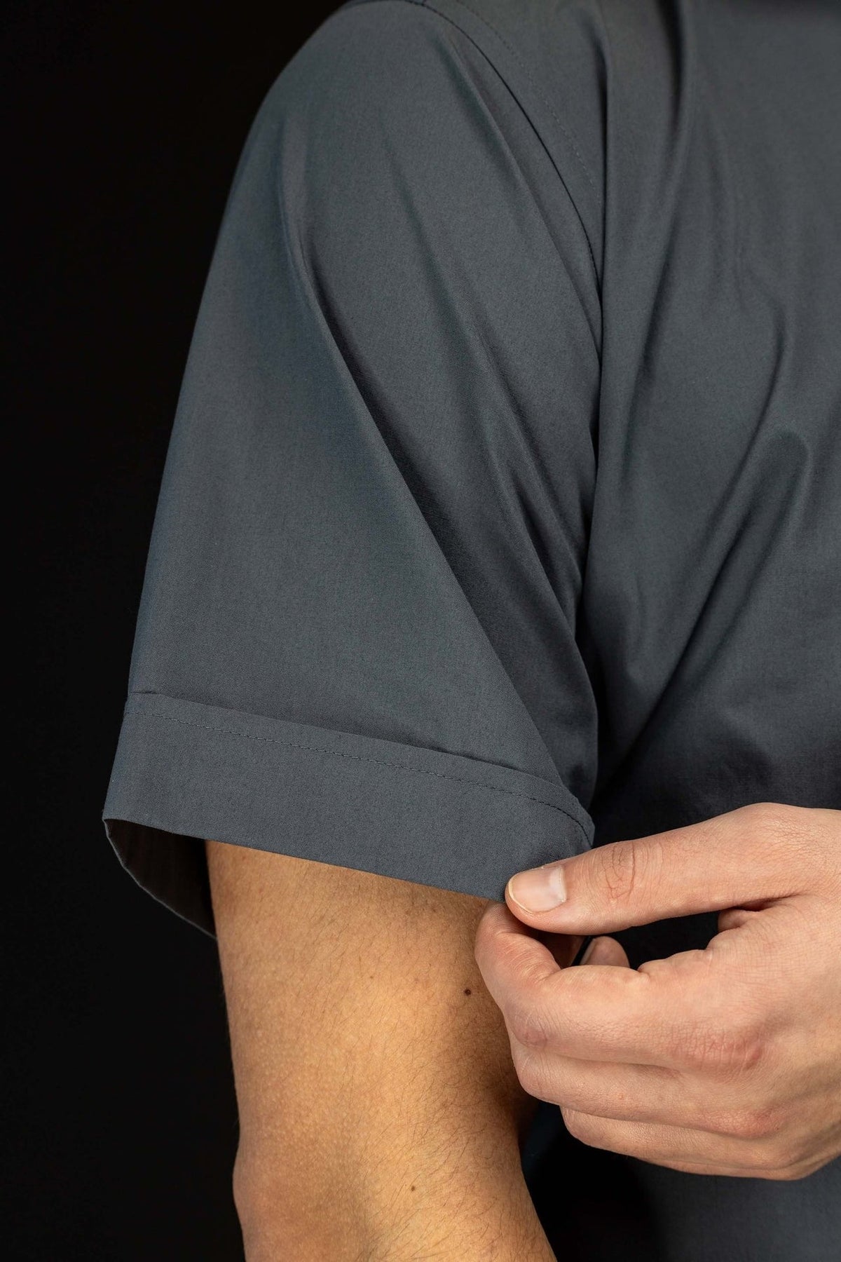 Camisa clerical cinza-escura com detalhe da manga curta e barra dobrada