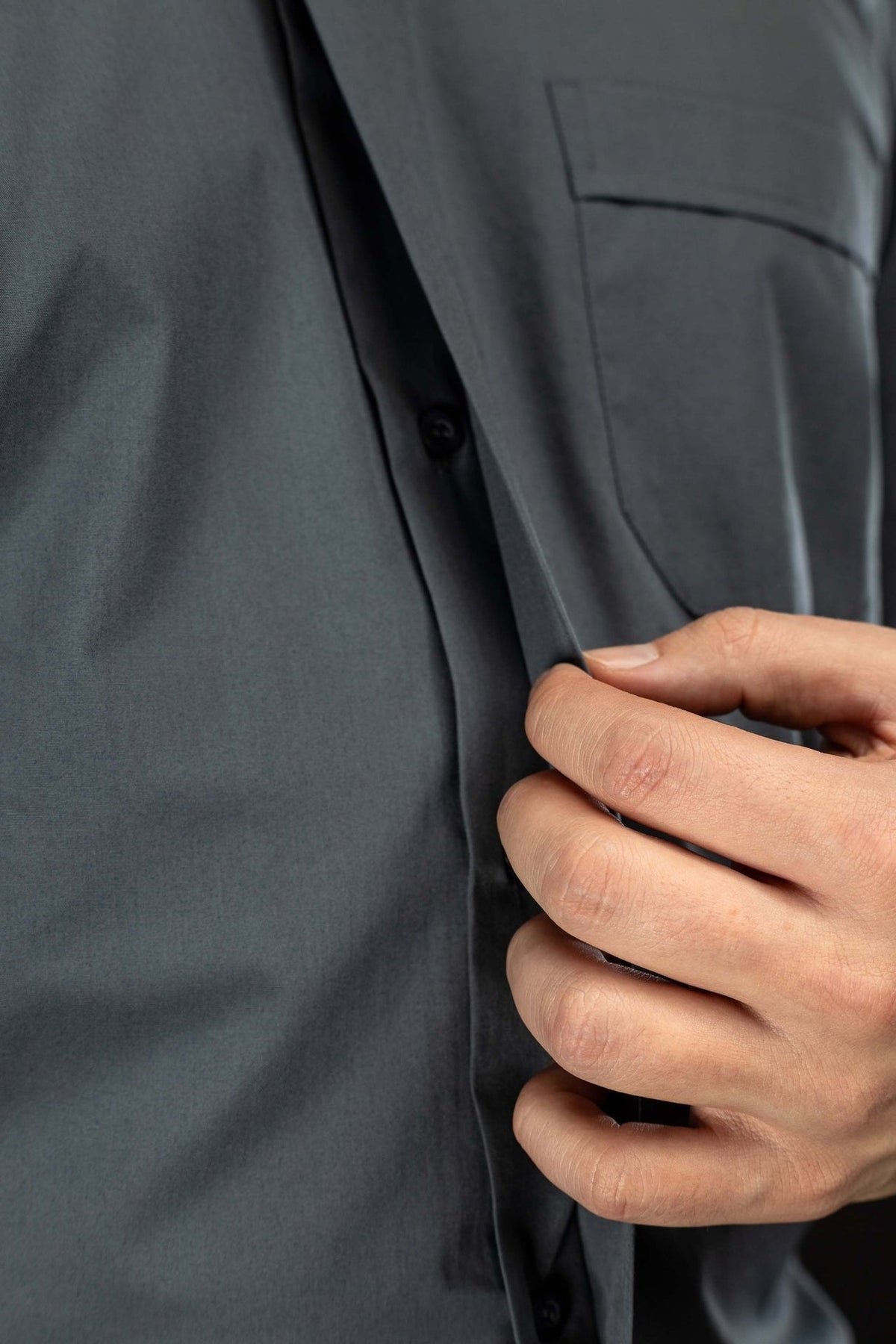 Camisa clerical cinza-escura com vista aproximada da abertura frontal e botão