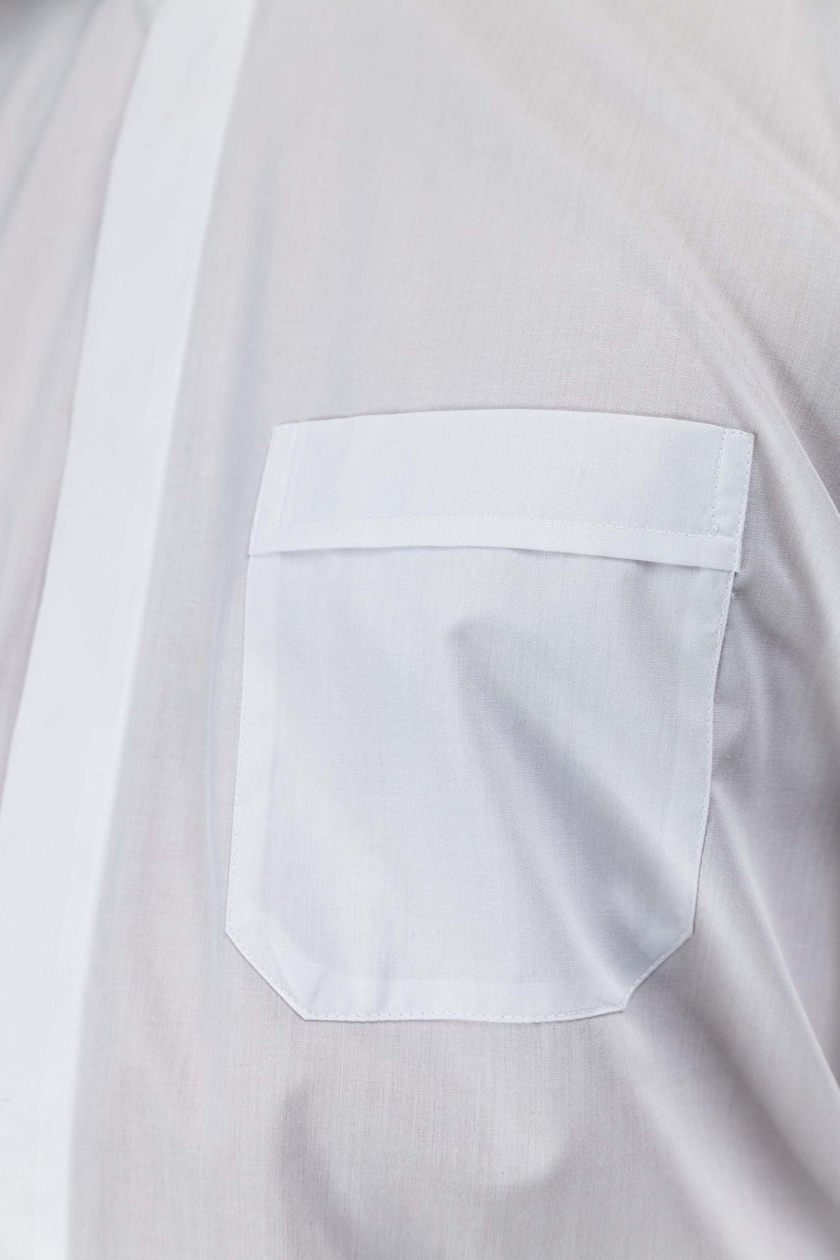 Camisa clerical branca em close-up do bolso frontal com aba e cantos chanfrados
