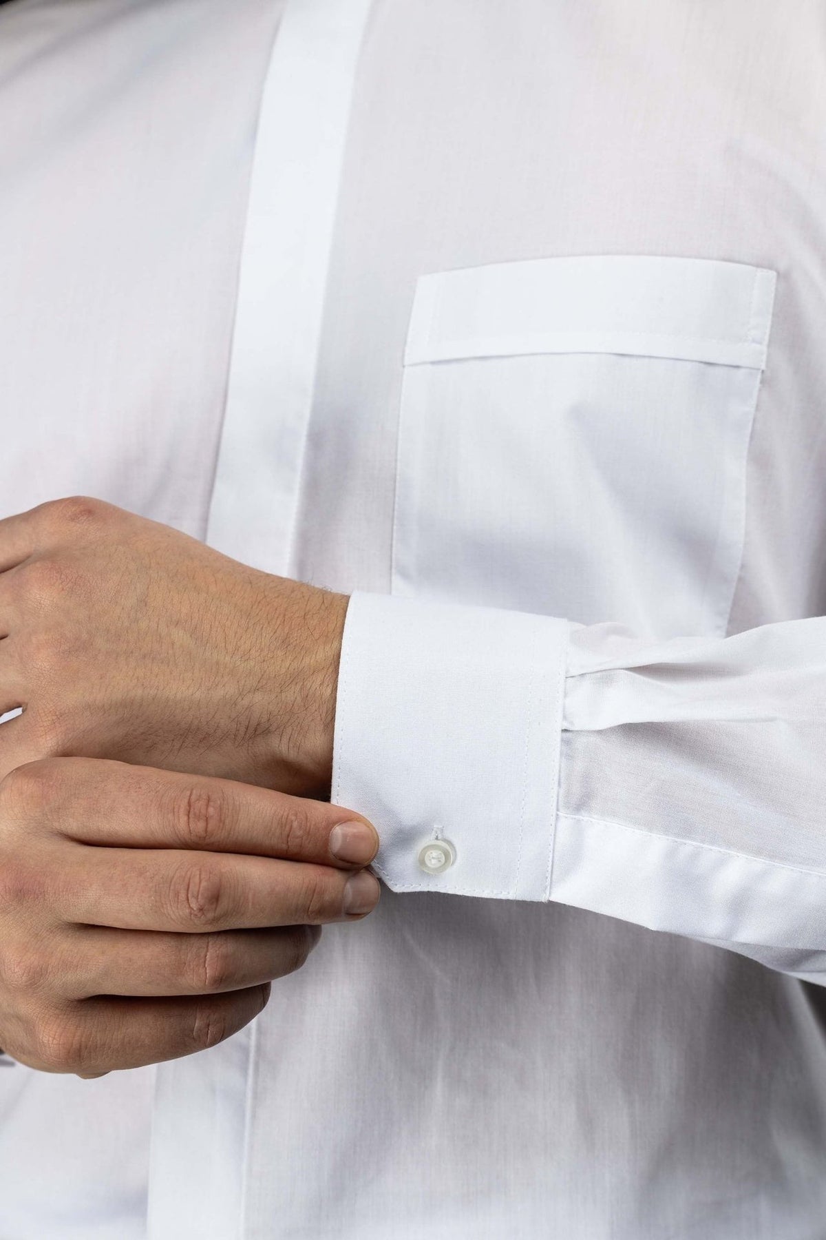 Camisa clerical branca em close-up do bolso frontal e punho de manga longa
