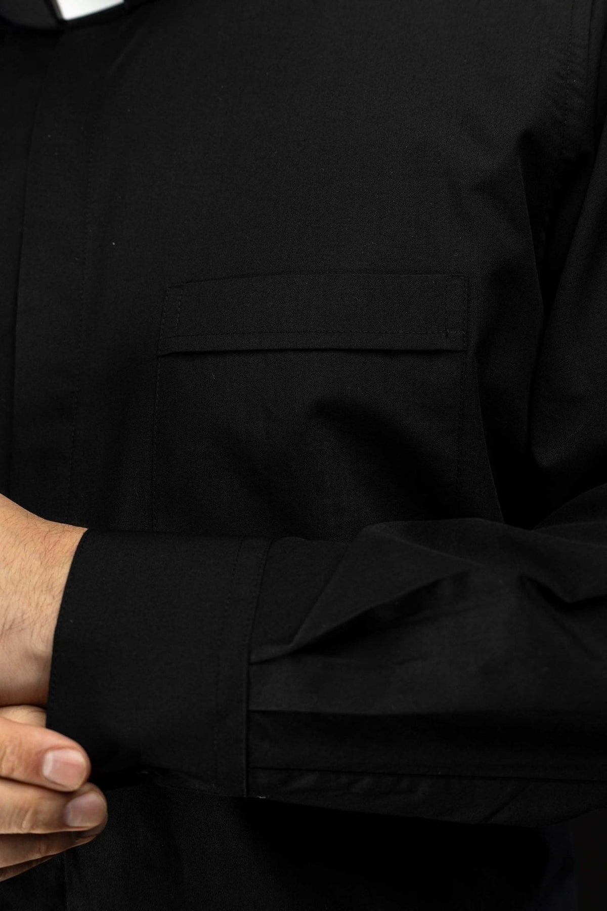 Camisa clerical preta em close-up, mostrando bolso frontal com aba