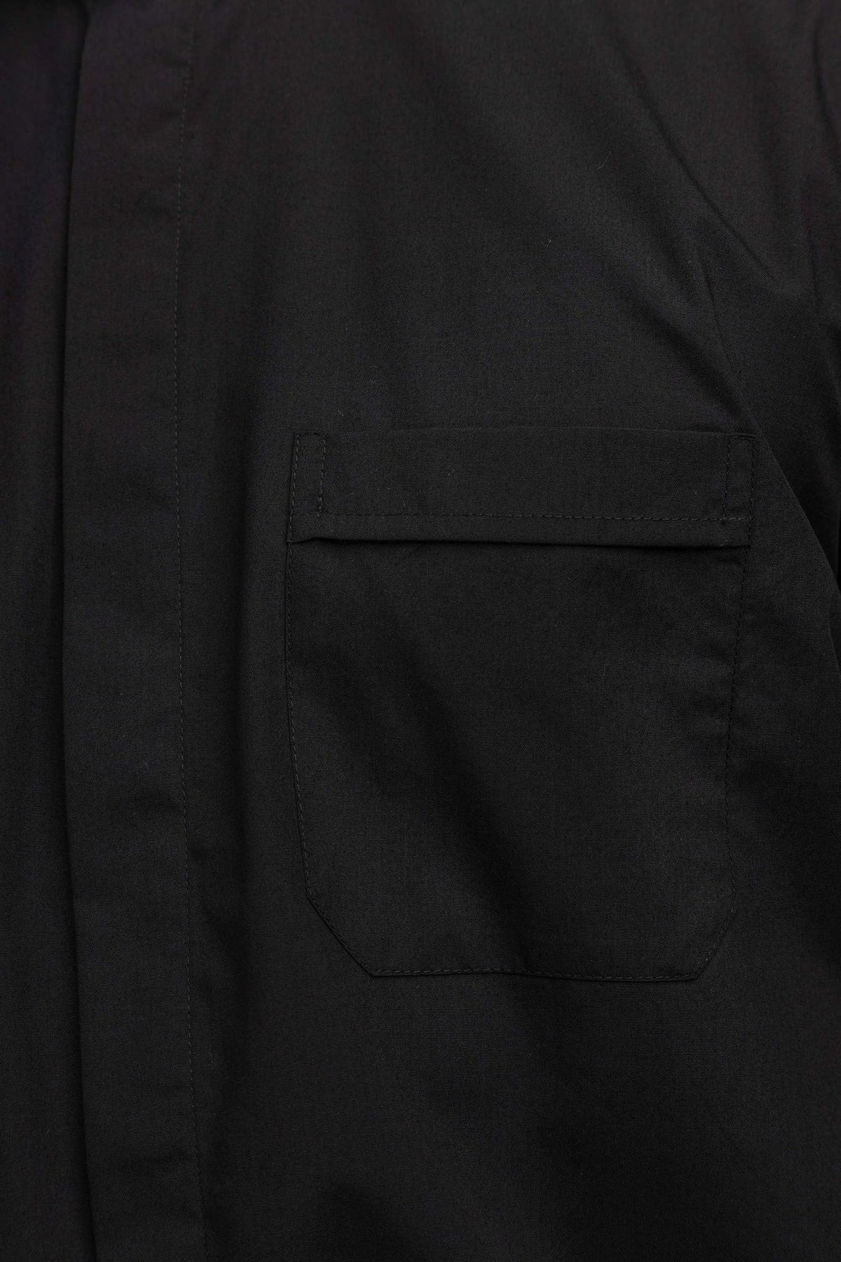 Camisa clerical preta com close-up do bolso frontal com aba
