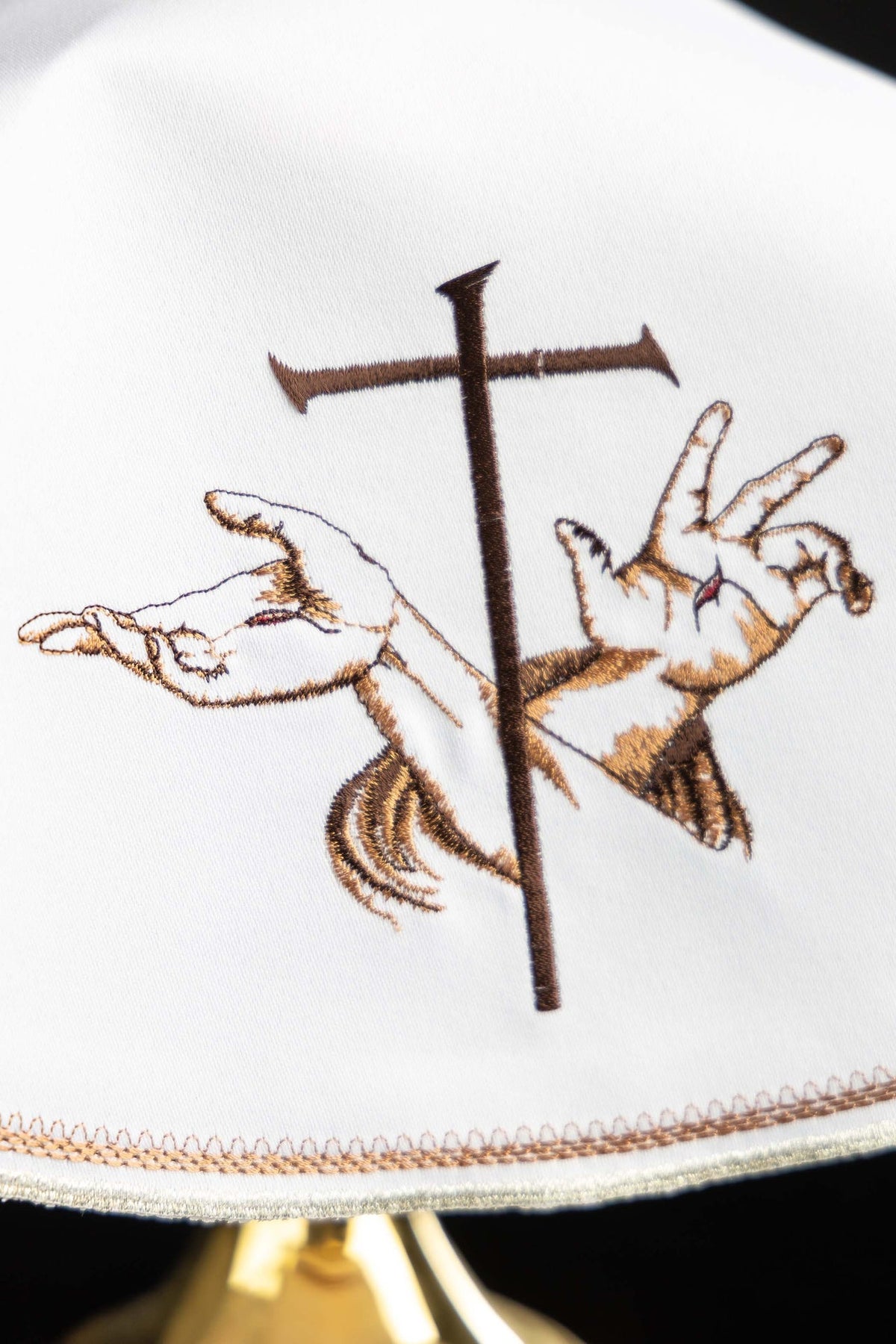 Véu de âmbula branco em close-up, com bordado franciscano e acabamento dourado
