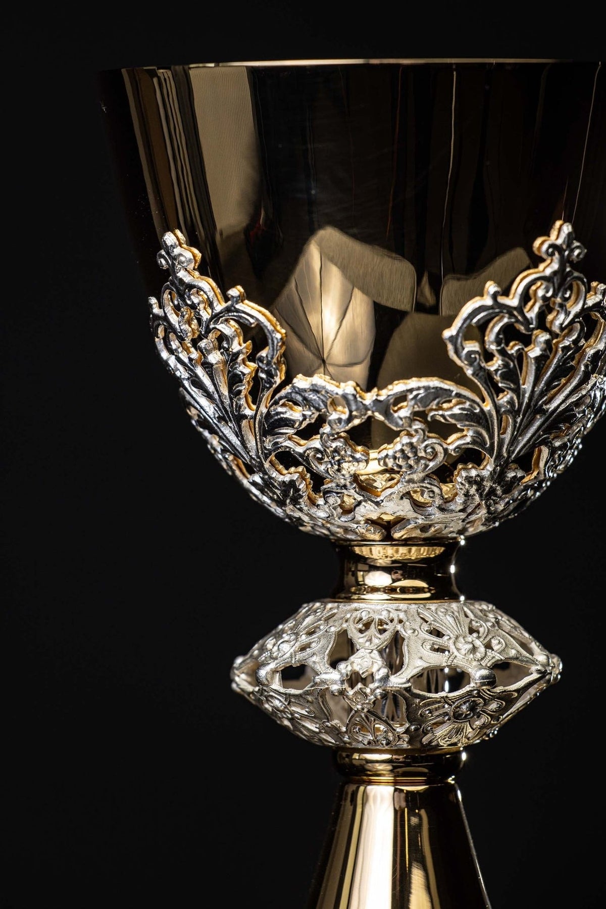 Cálice dourado com ornamentos prateados, close-up frontal da taça e suporte