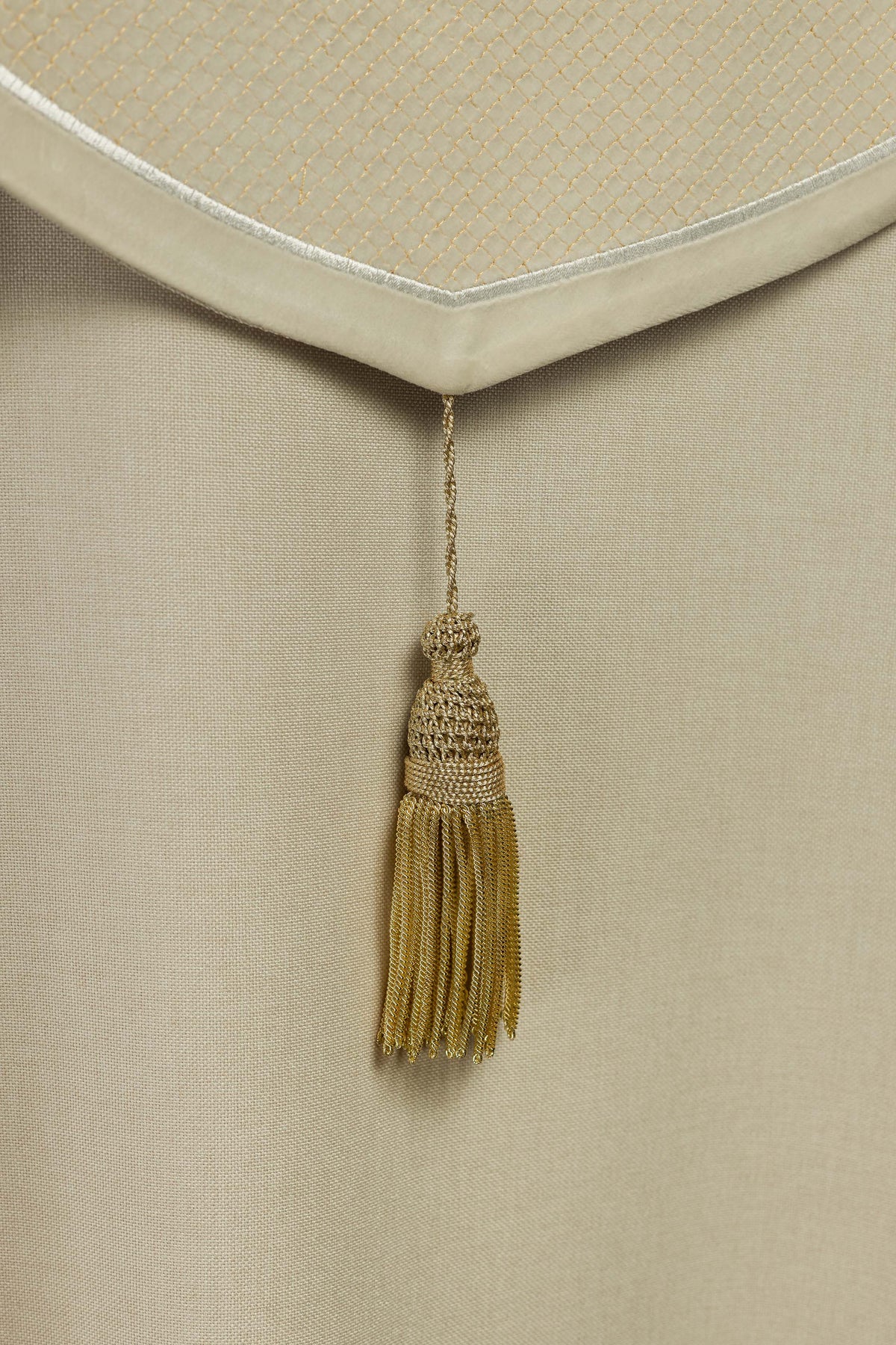 Capa de asperges creme em close no pingente dourado com franjas