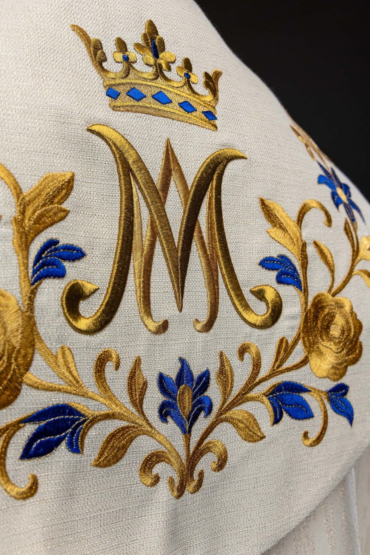Capa de asperges com close-up de flores bordadas em azul e dourado